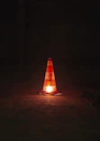 A traffic cone sitting on the ground at night