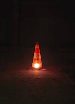 A traffic cone sitting on the ground at night