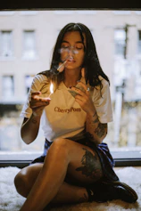 A woman sitting on the floor smoking a cigarette