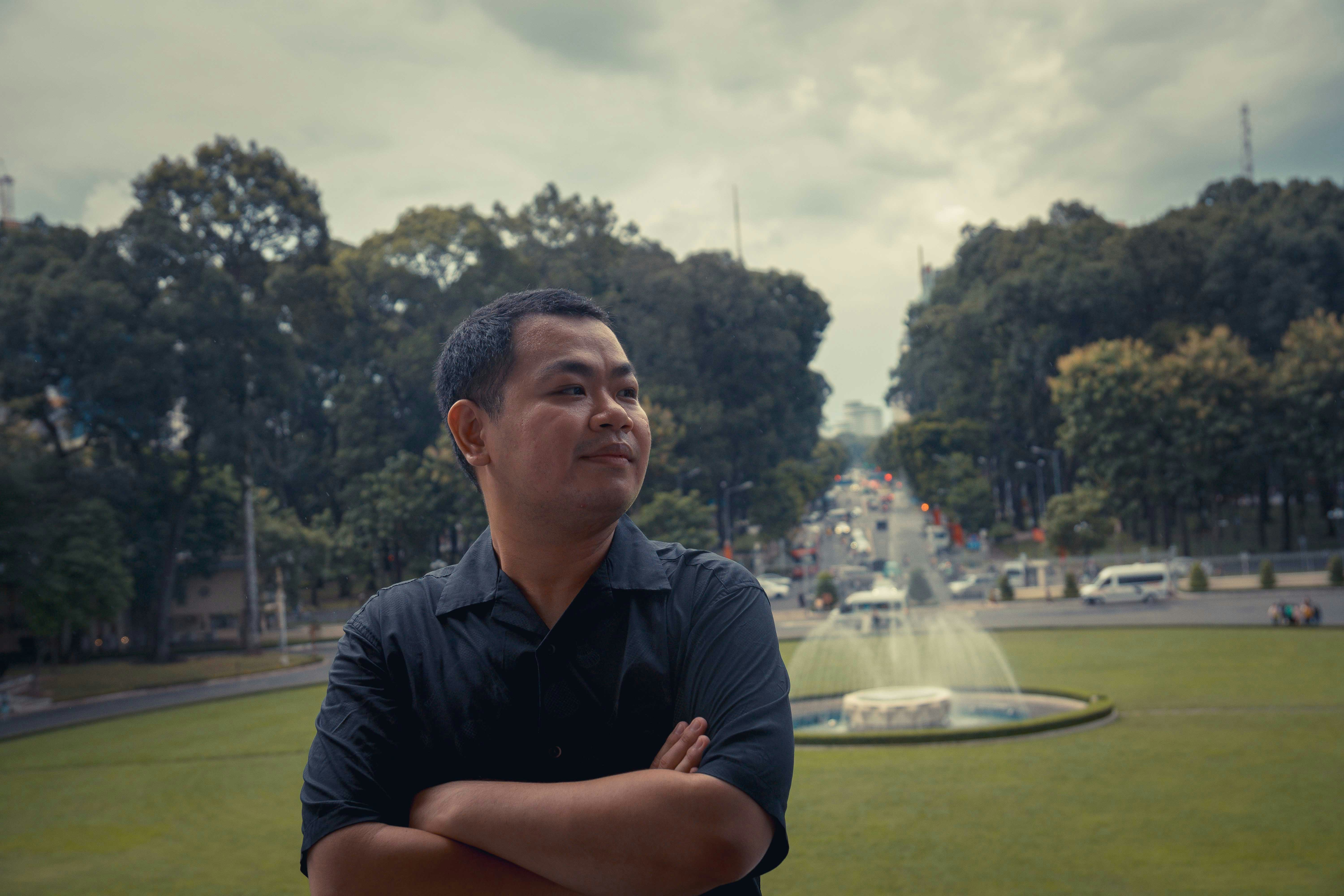 Seorang pria berdiri di depan air mancur di taman