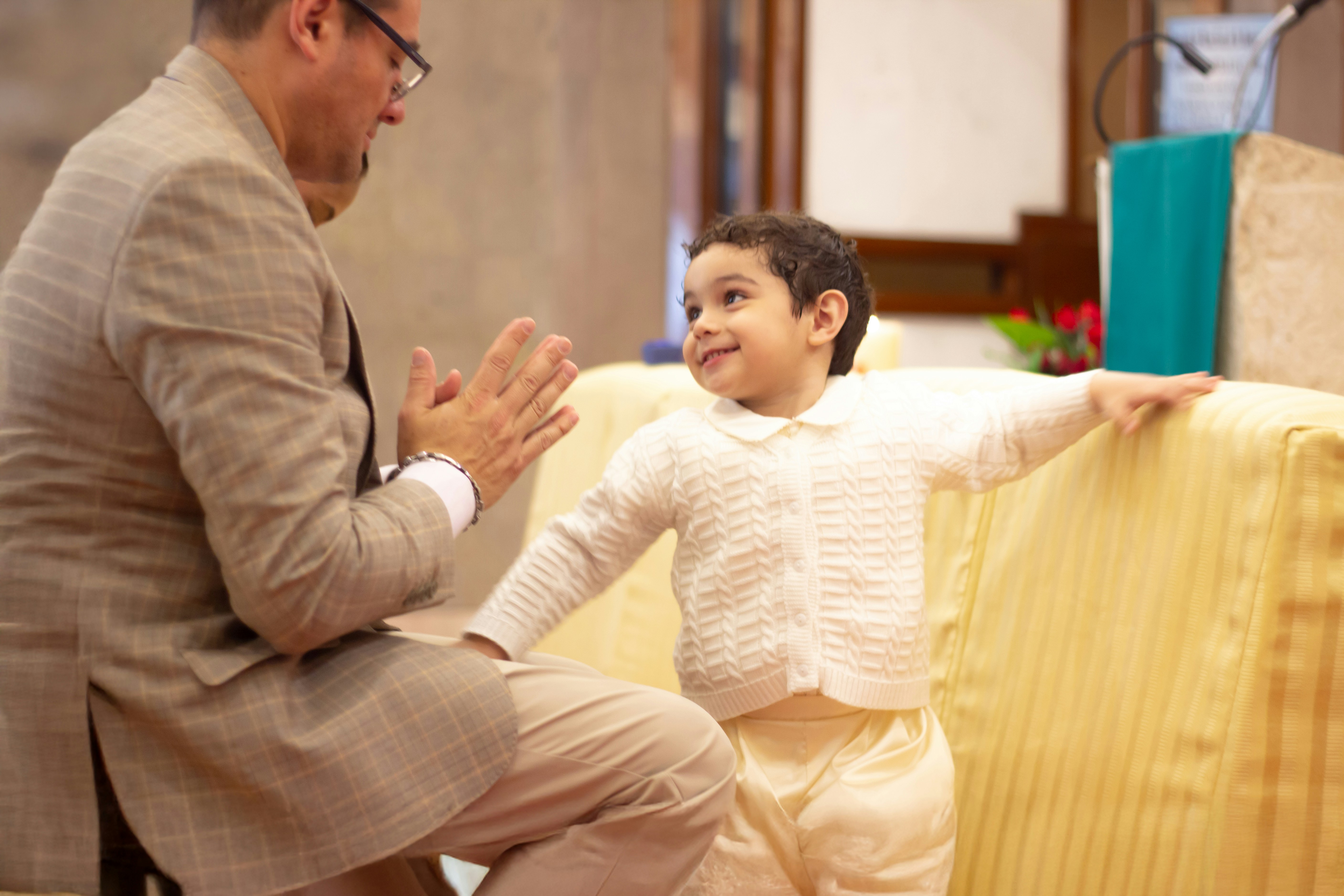 A father and child laughing while roughhousing on a living room rug, showing a joyful and safe interaction.