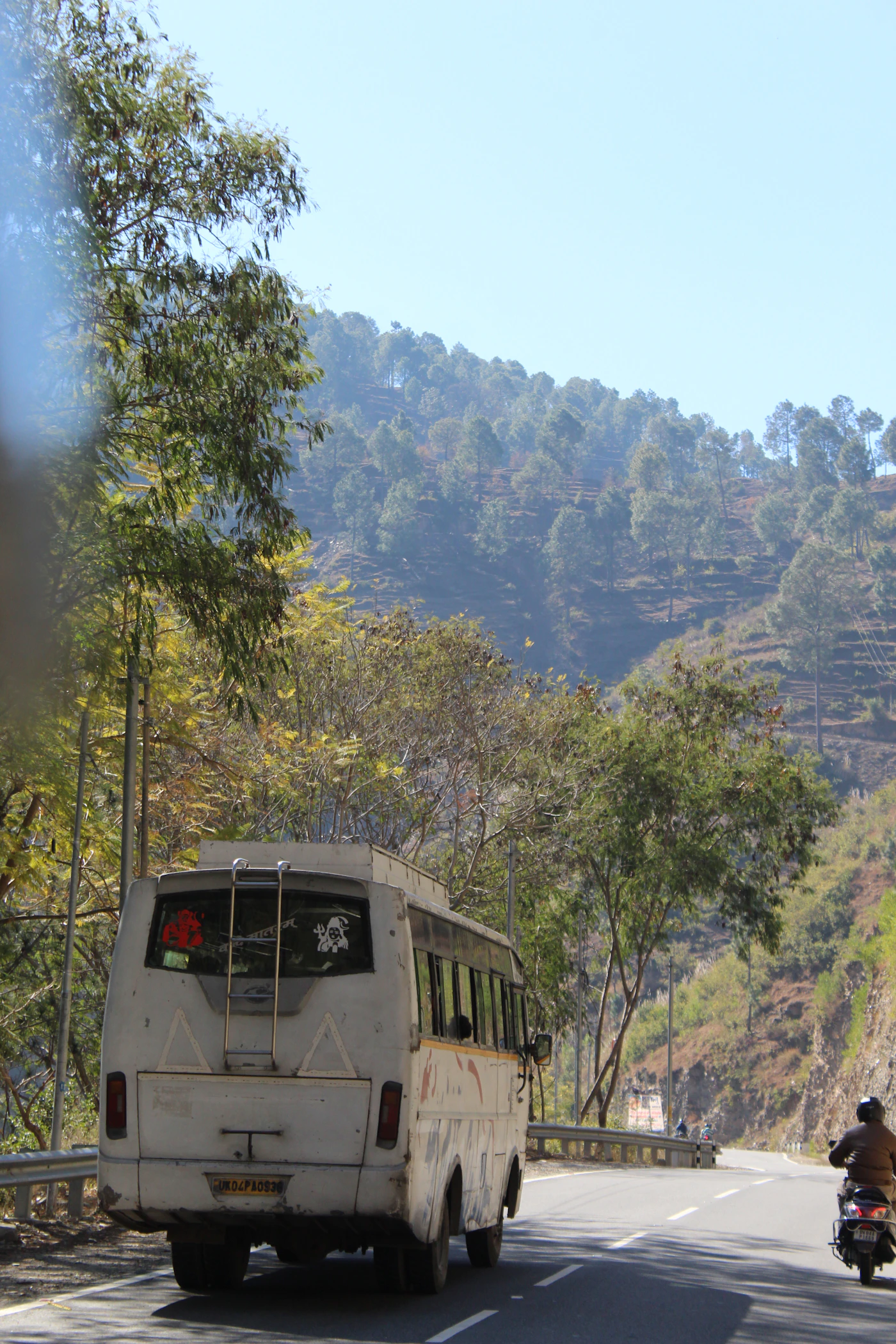 White AC coach travelling along a forest road