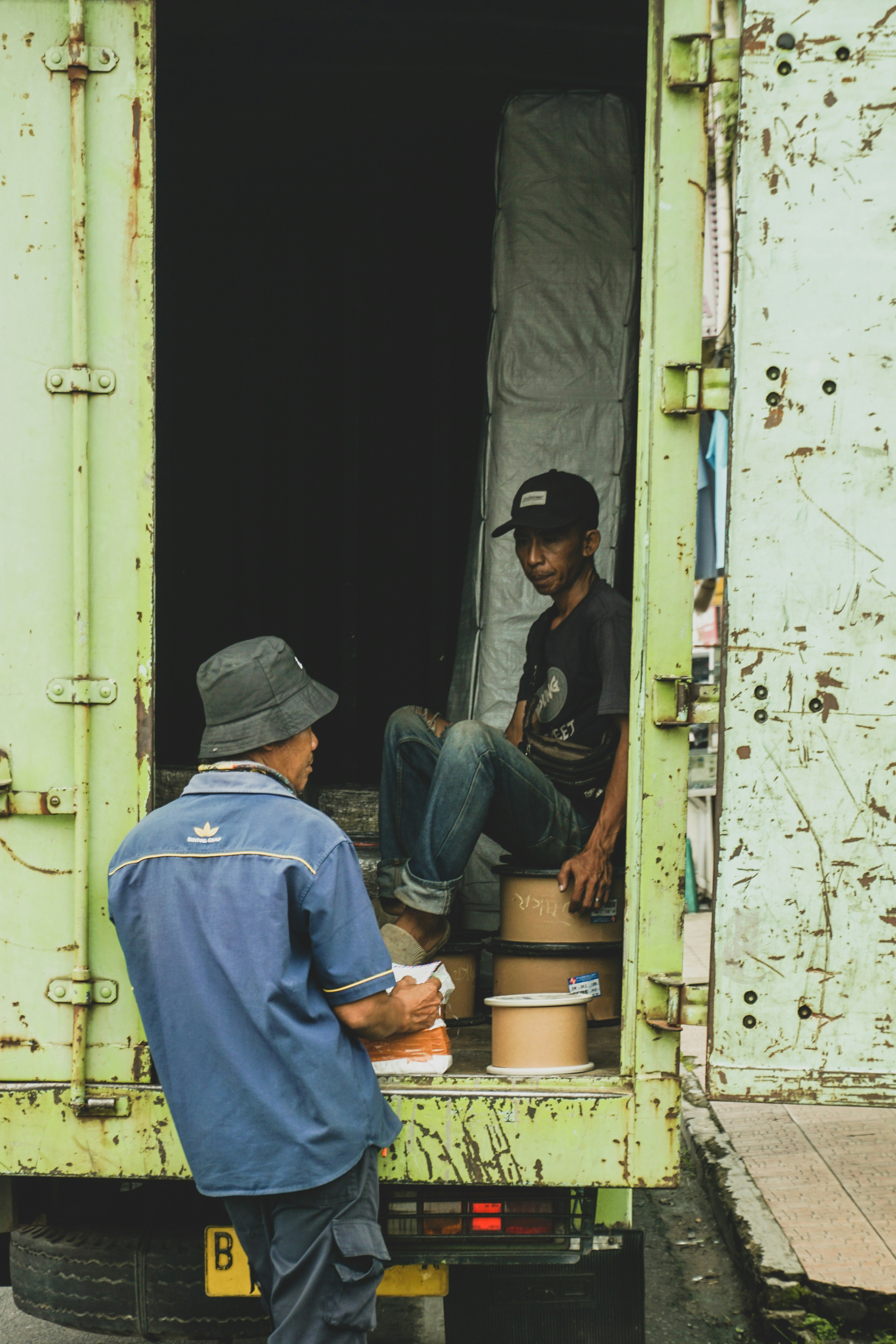 Zwei Männer sitzen auf der Ladefläche eines grünen Lastwagens