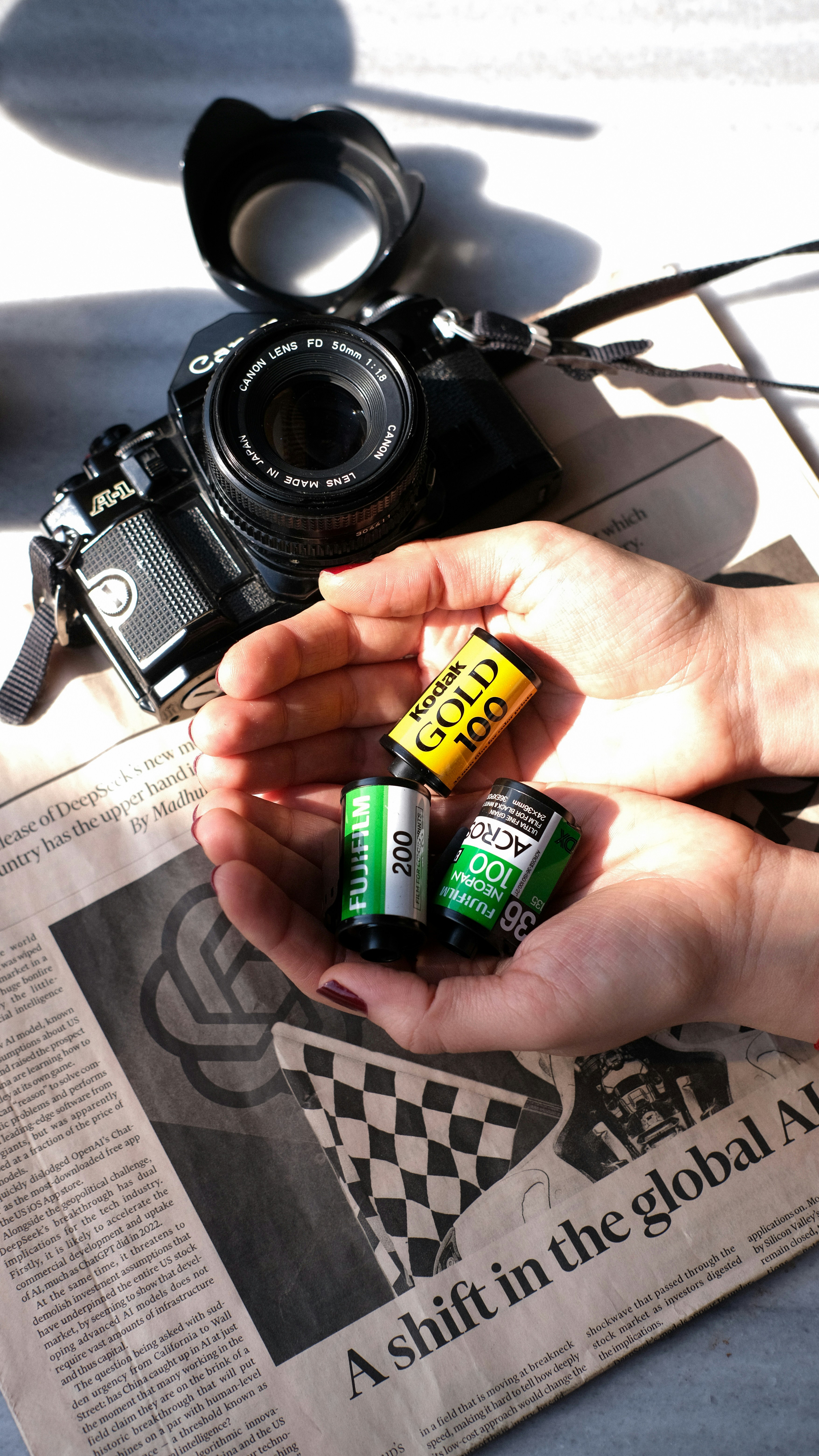 A person holding three batteries next to a camera