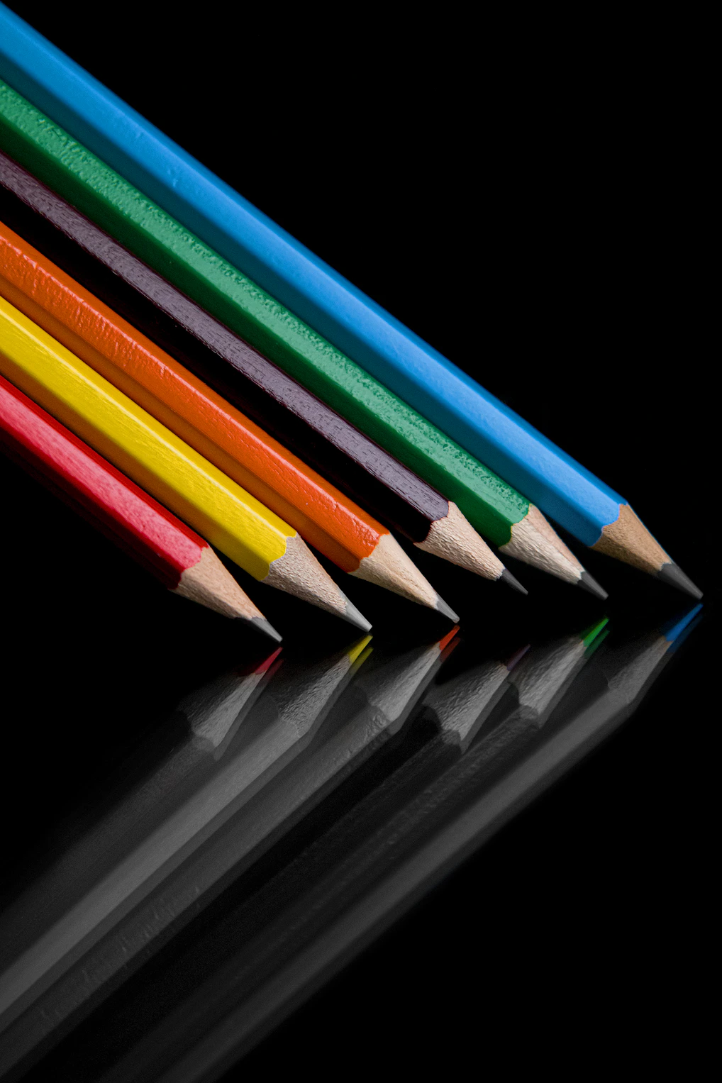 A row of colored pencils on a black background