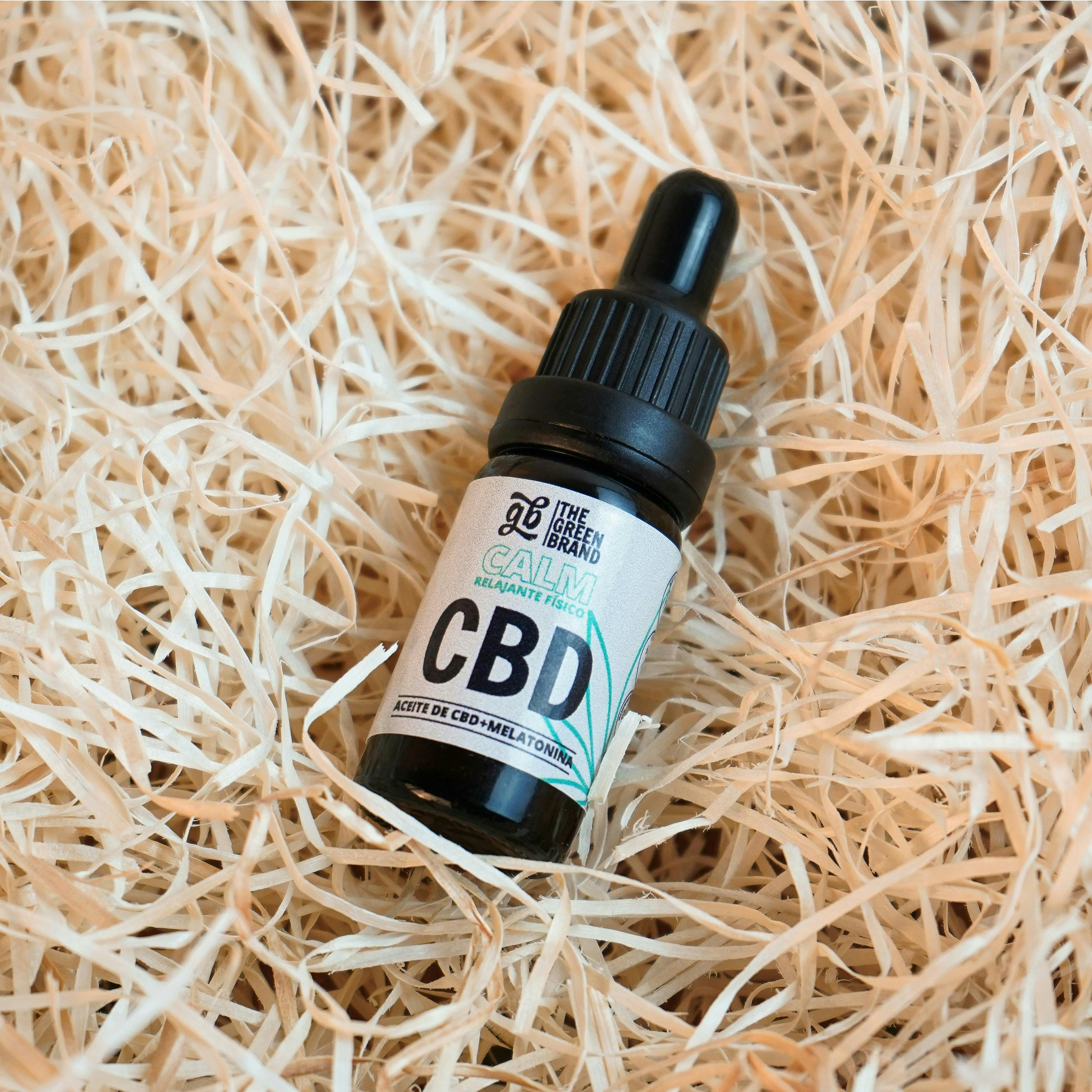 A bottle of cbd sitting on a bed of straw