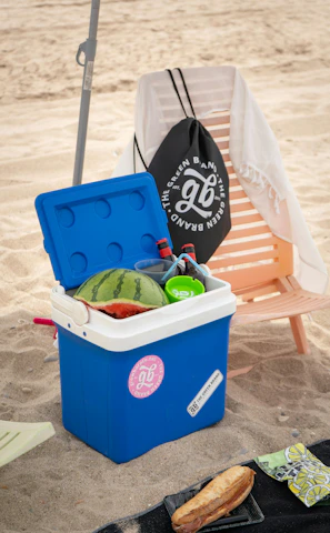 A cooler sitting on a beach next to a chair