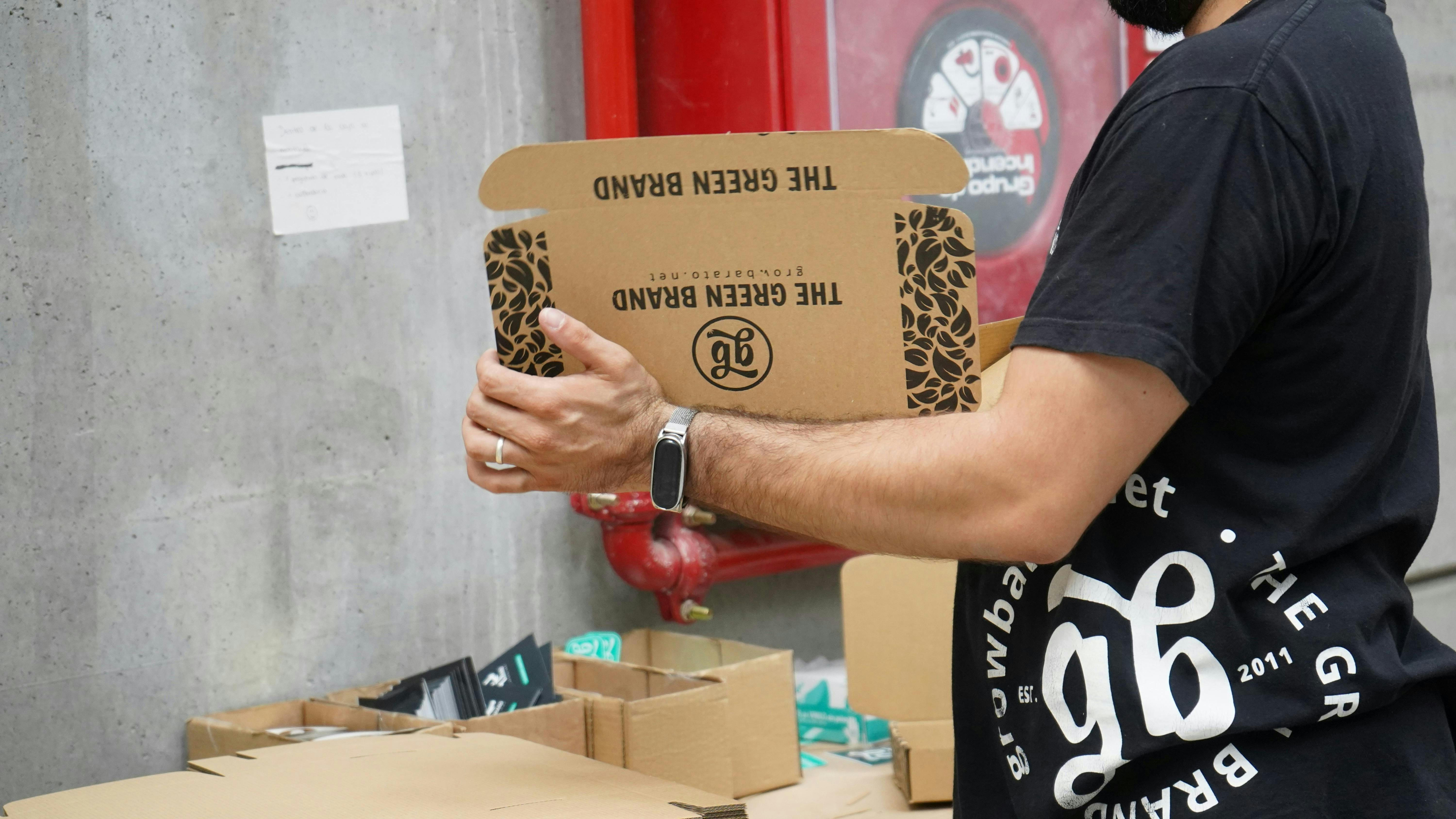 A man holding a cardboard box in front of a red fire hydrant