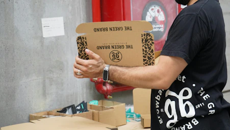 A man holding a cardboard box in front of a red fire hydrant