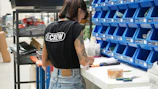 A woman standing in front of a shelf of blue bins