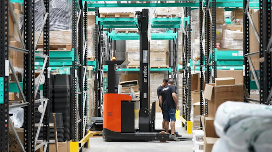 A man standing in a warehouse with a fork lift