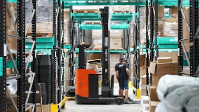 A man standing in a warehouse with a fork lift