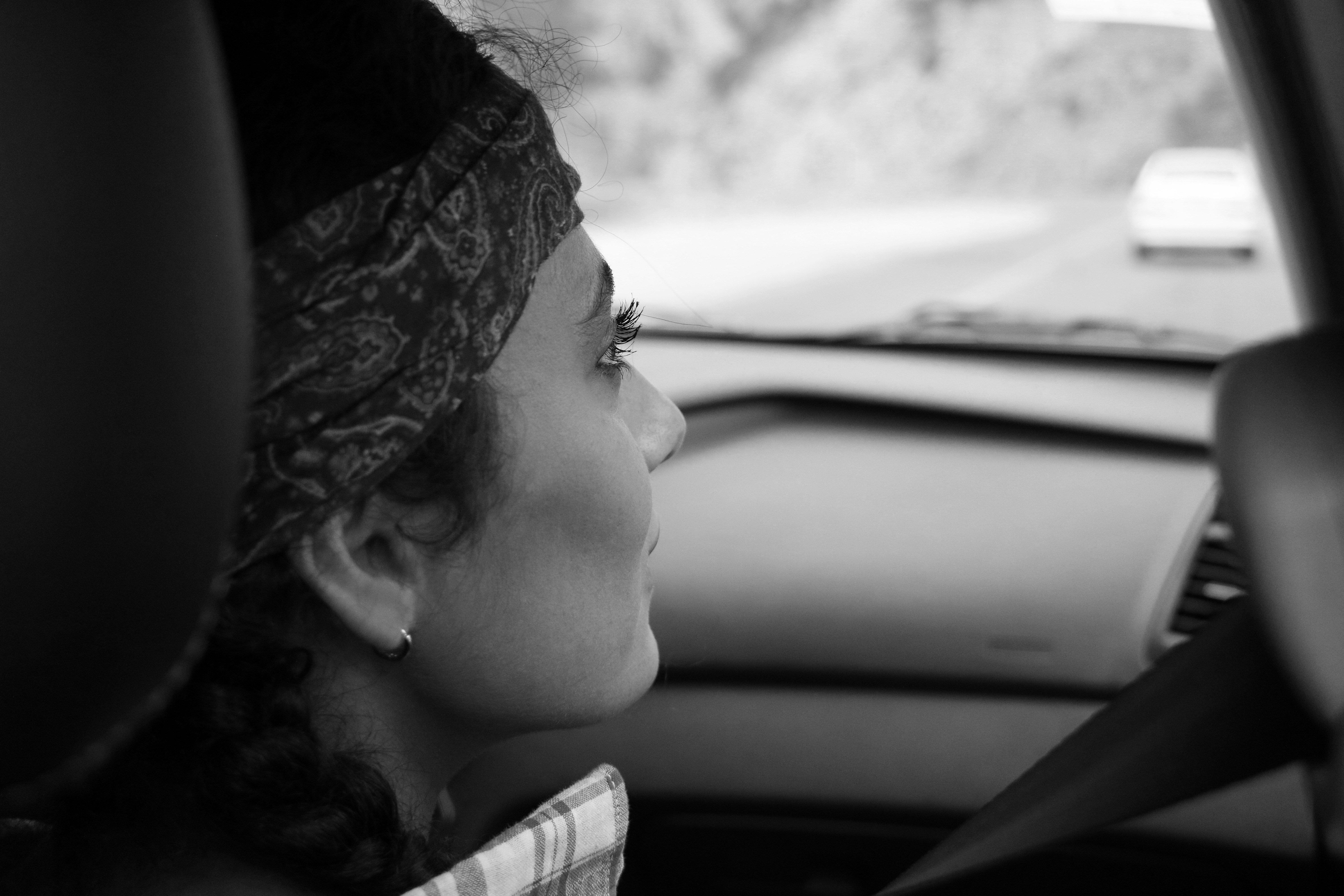 A woman driving a car with a scarf on her head
