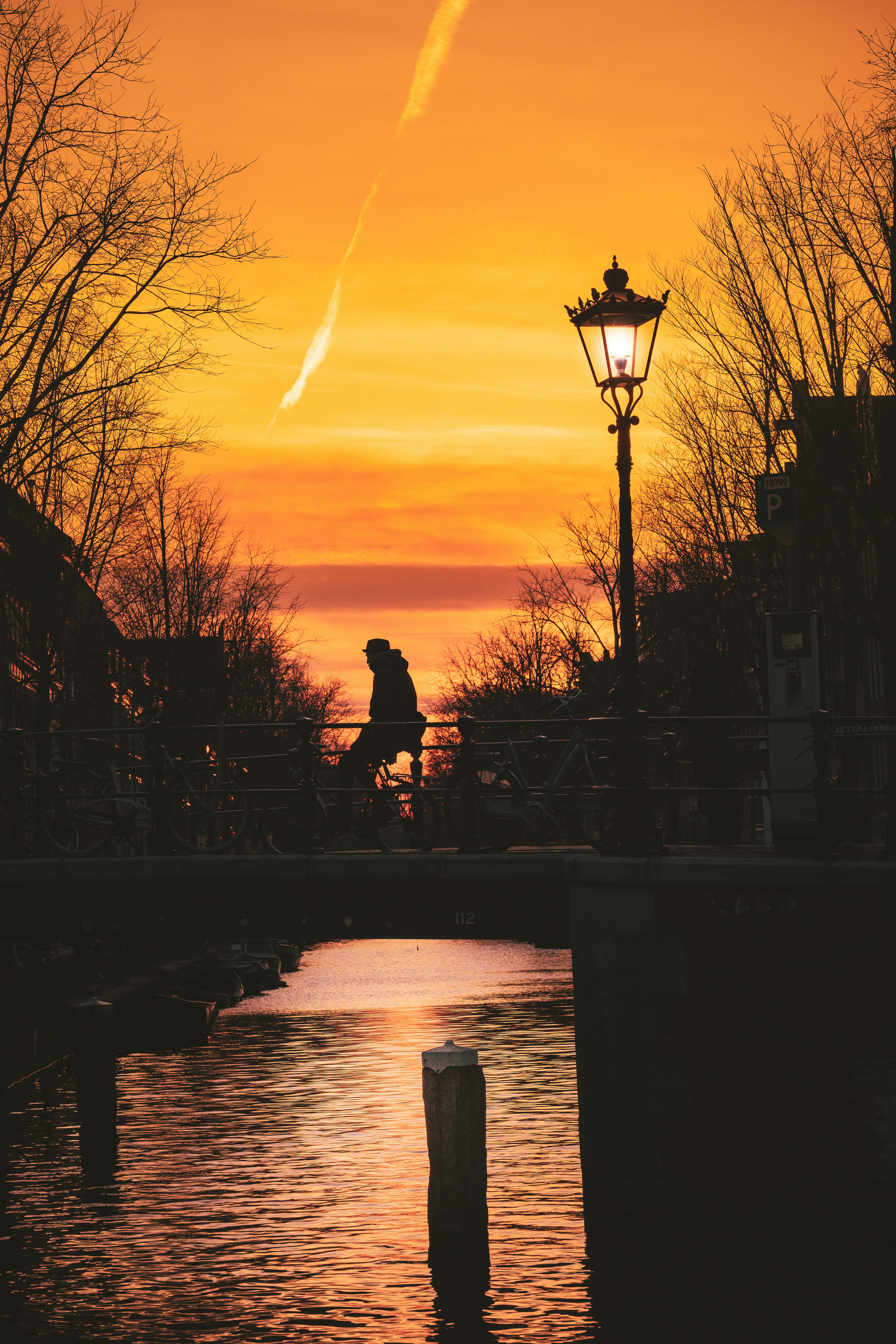 Eine Person, die bei Sonnenuntergang mit dem Fahrrad über eine Brücke fährt