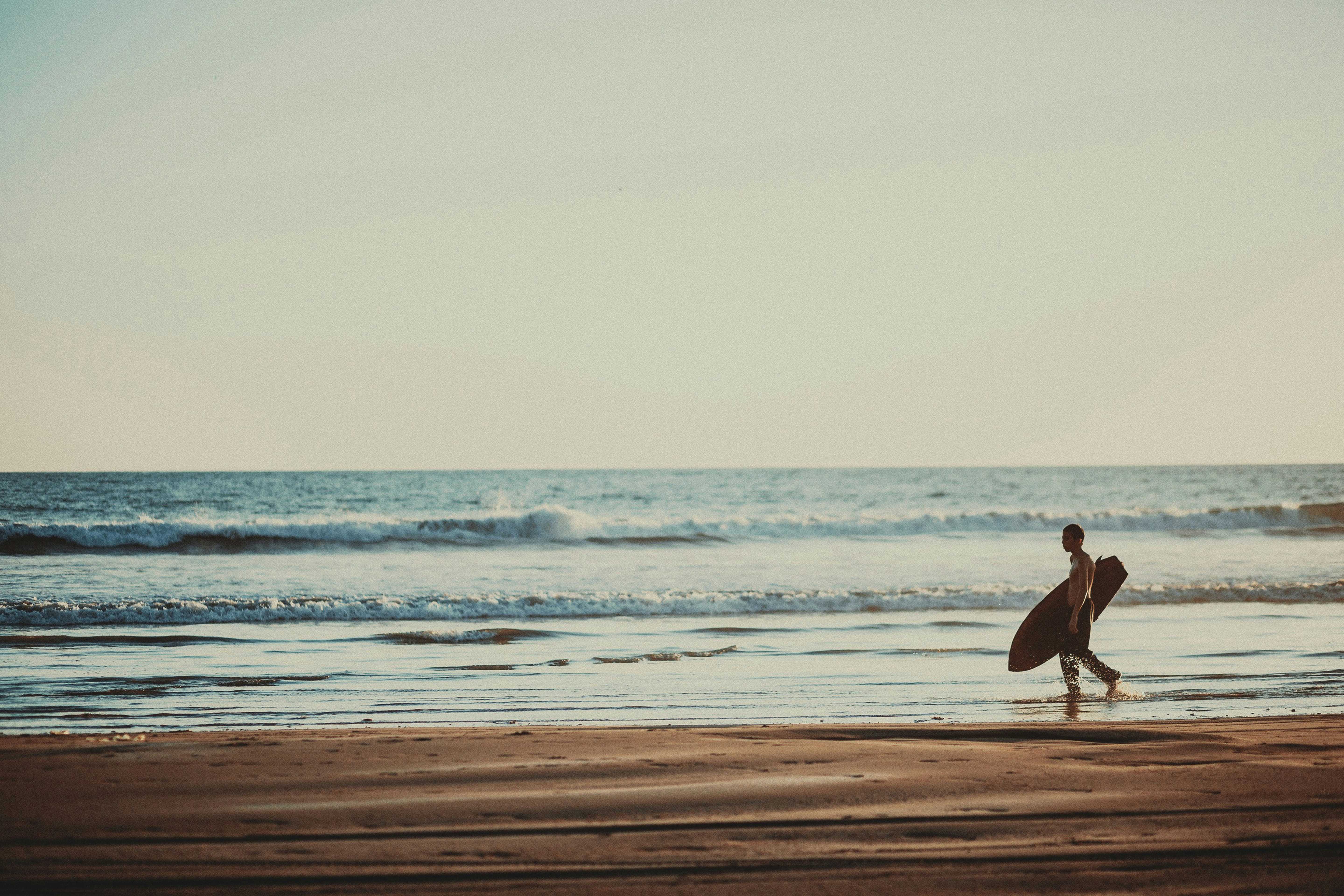 A person walking on a beach with a surfboard