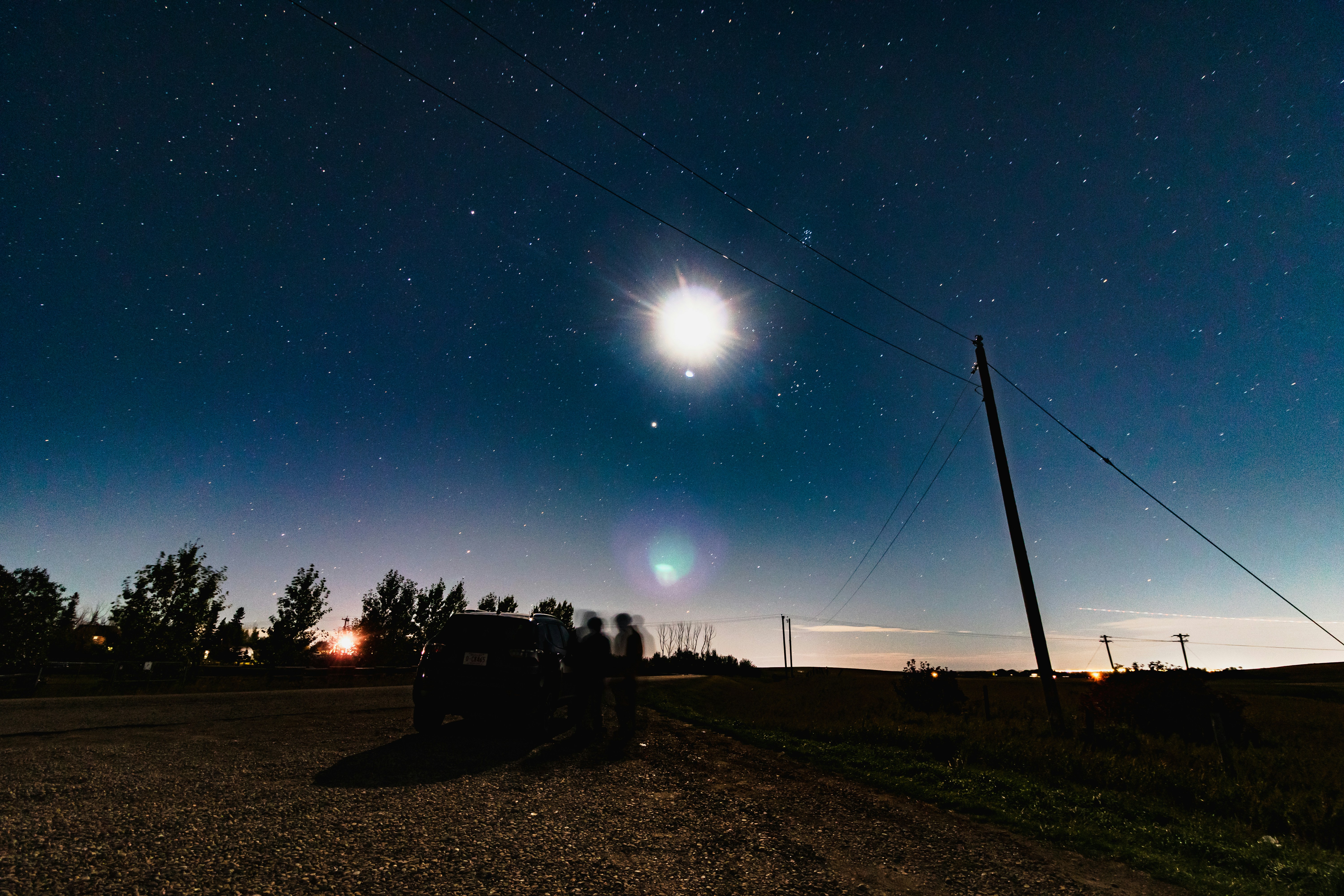 A night sky with the moon and stars in the distance