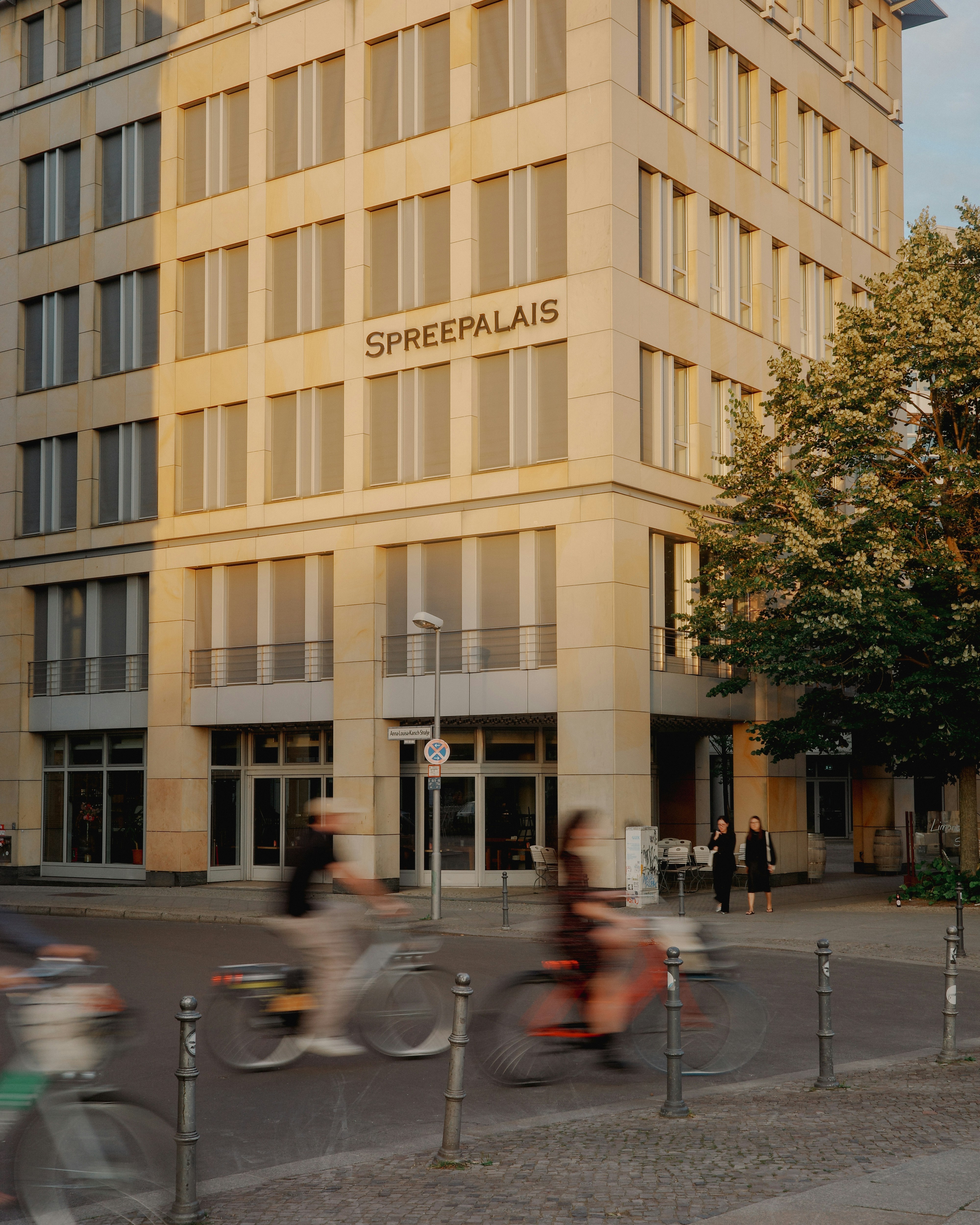 A group of people riding bikes past a tall building