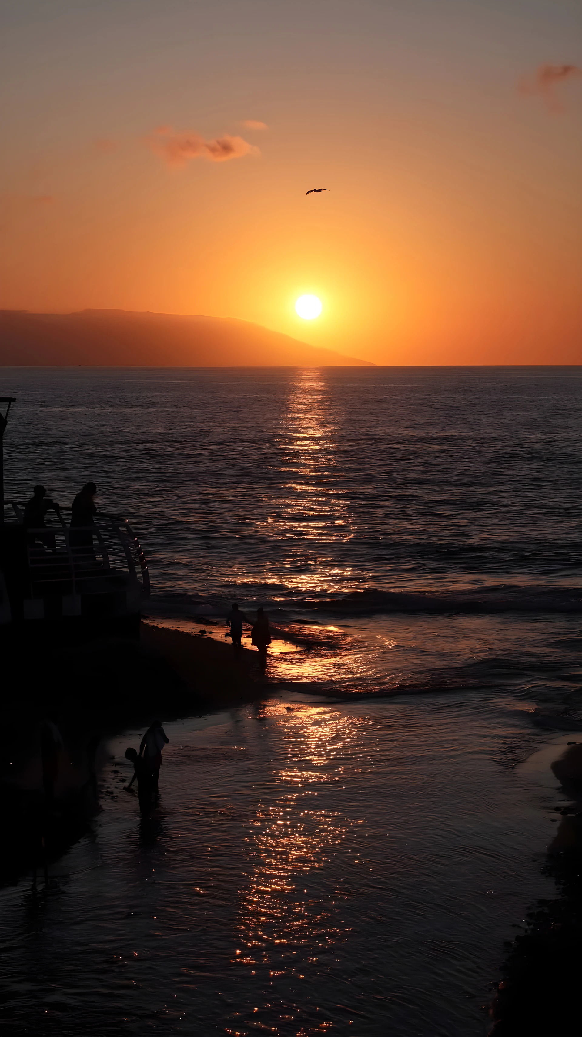 The sun is setting over the ocean with a boat in the water