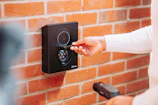A woman is pressing a button on a brick wall