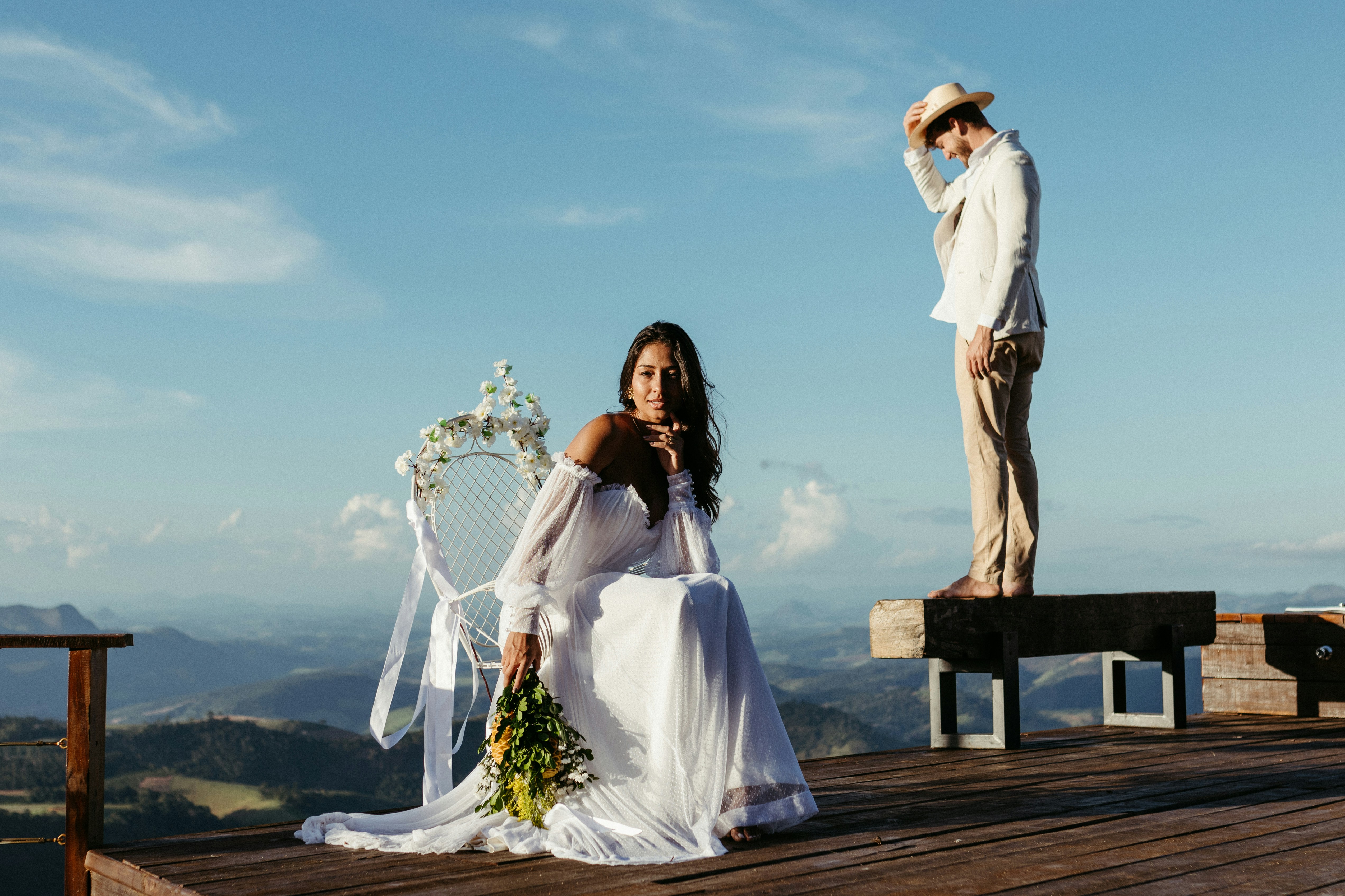 A bride and groom sitting on a wooden platform