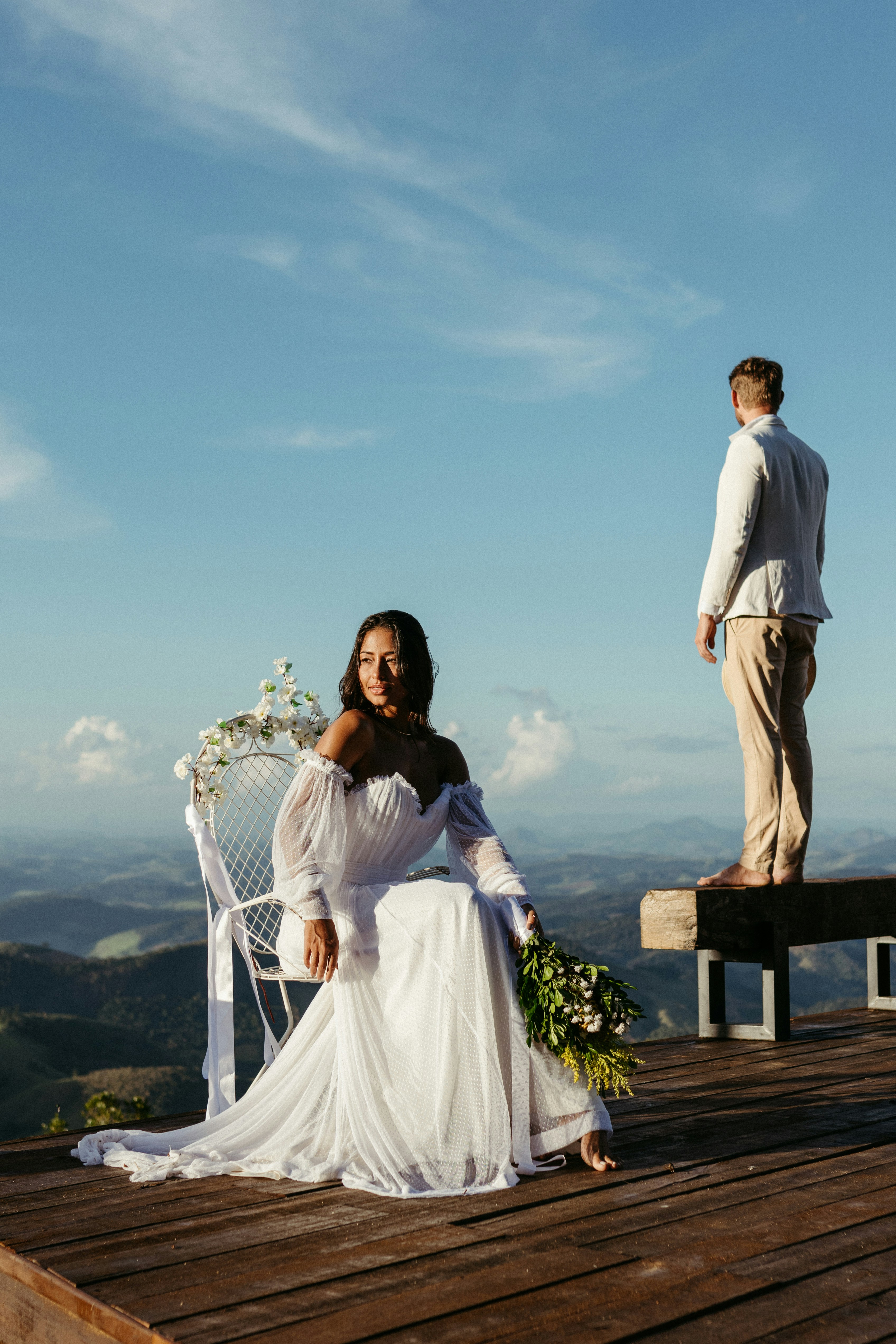 A woman in a wedding dress sitting on a bench
