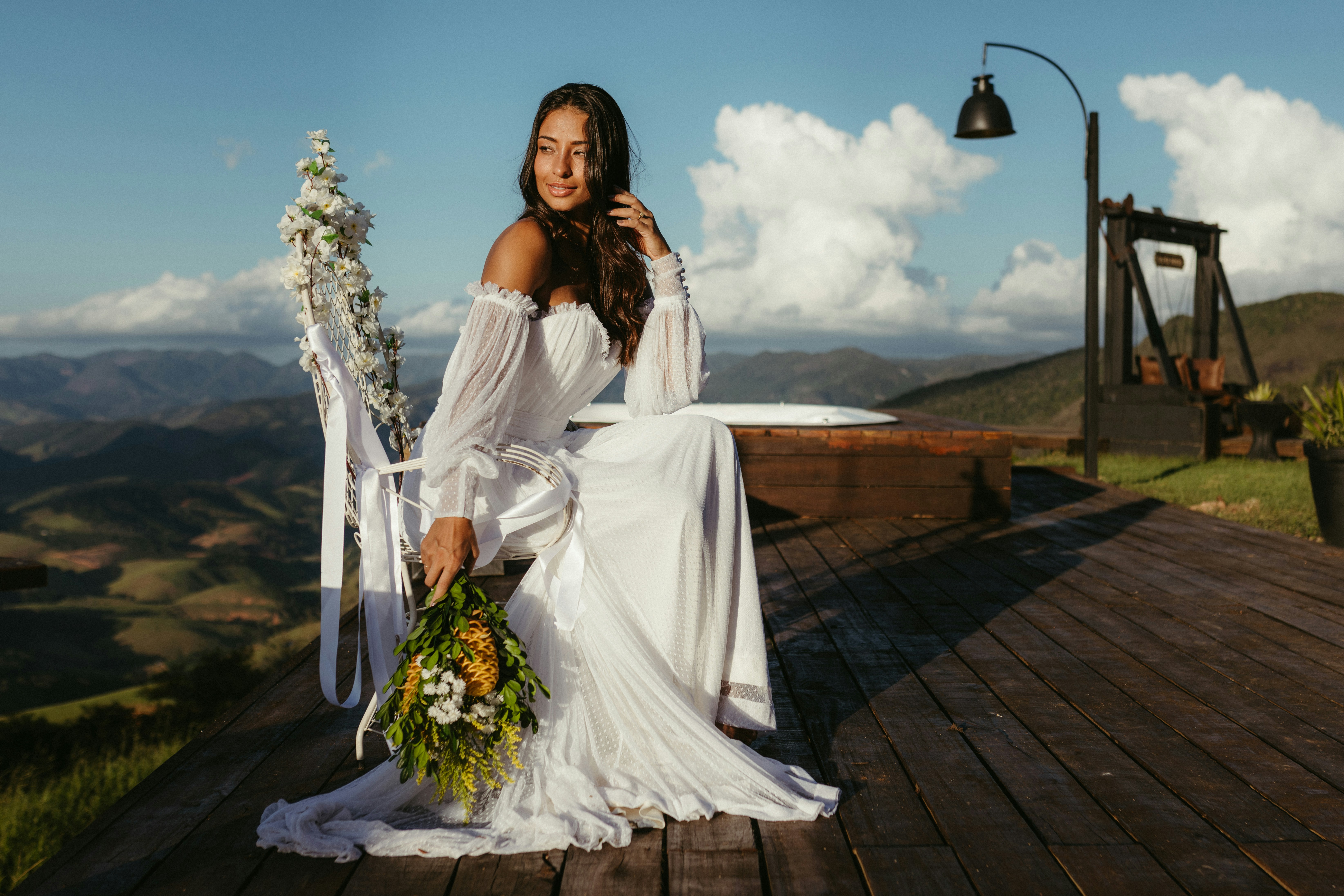 A woman in a white dress sitting on a wooden deck