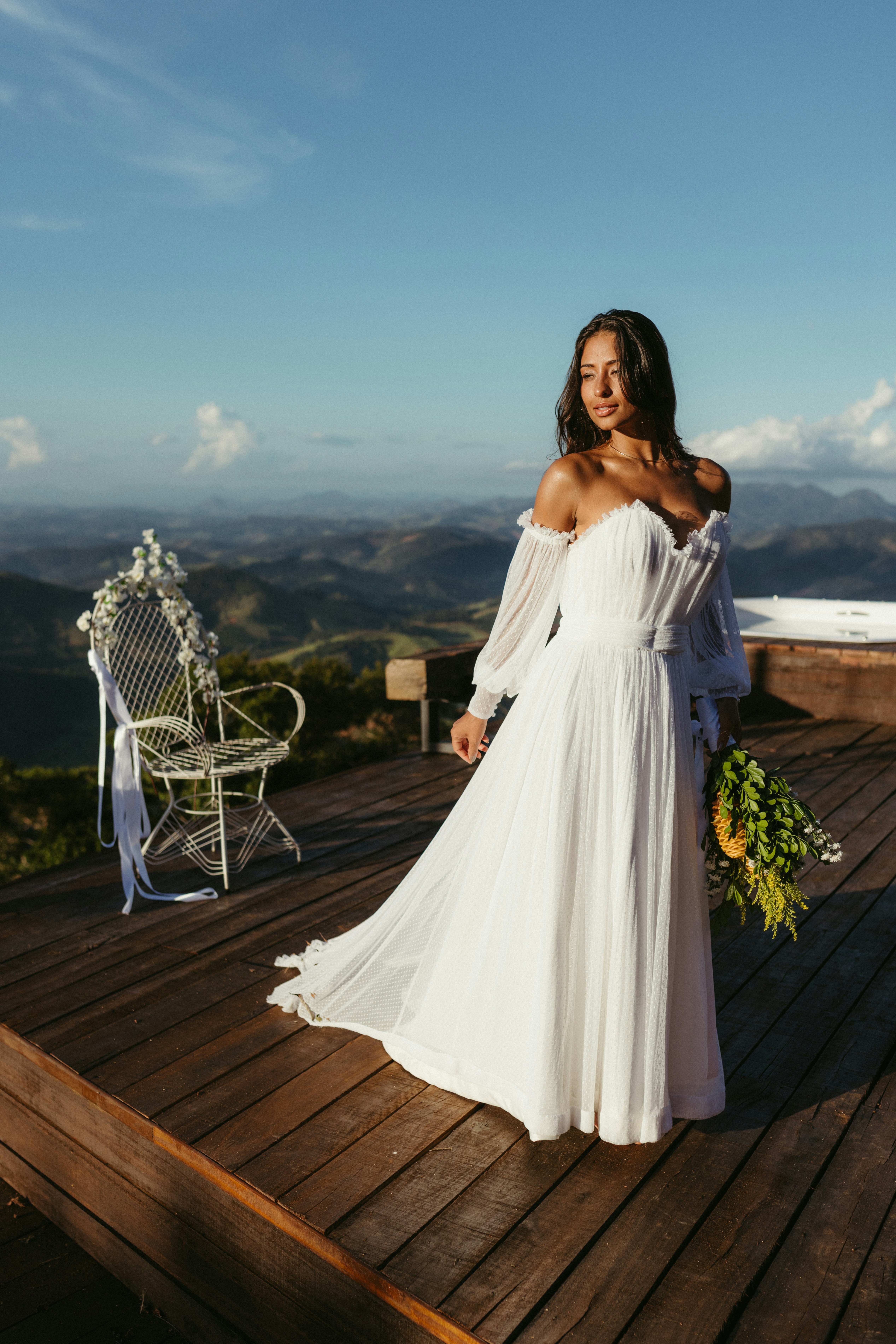 A woman in a white dress standing on a wooden deck