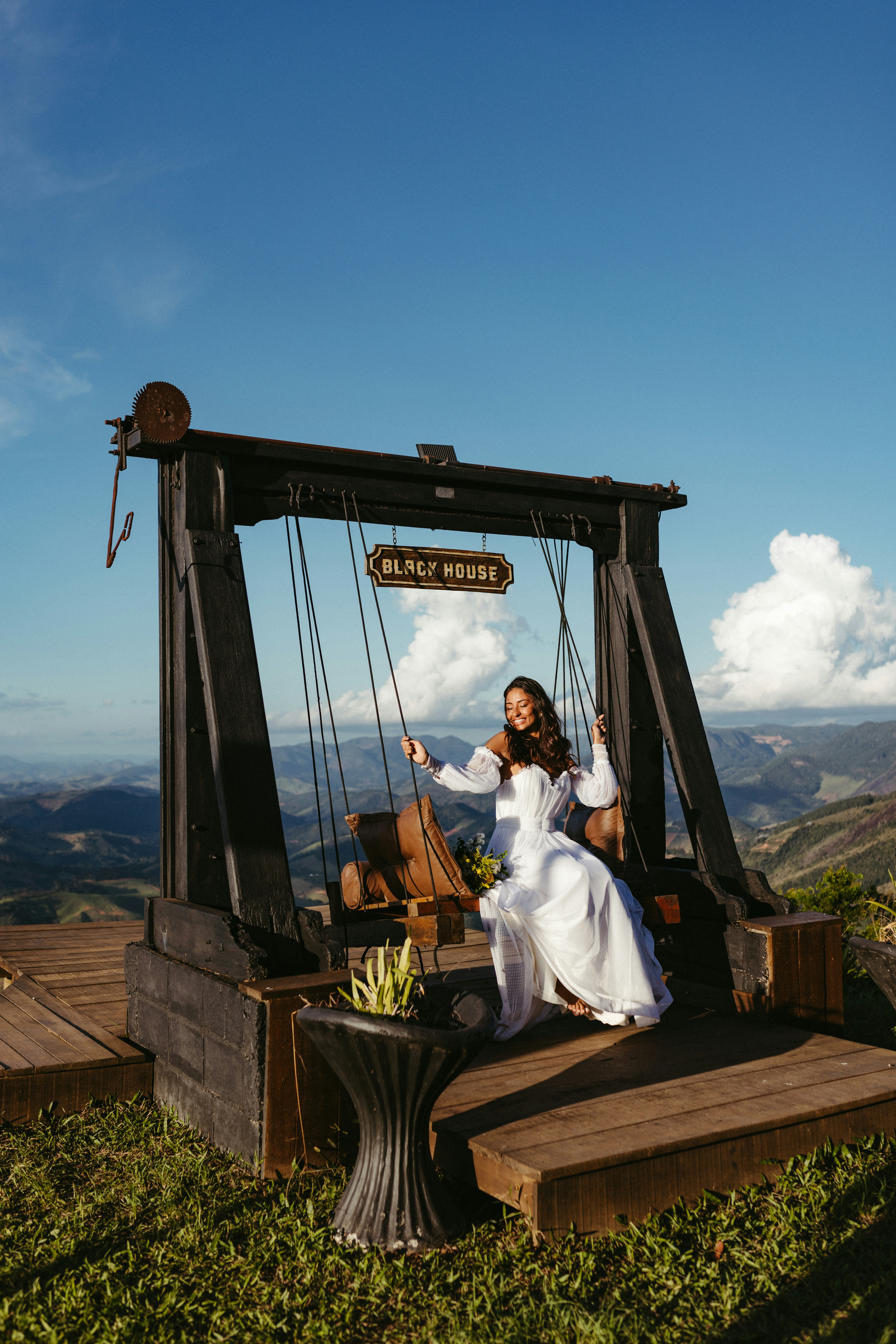A woman in a white dress is sitting on a swing