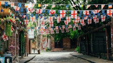 A narrow street with a lot of flags hanging from it's sides