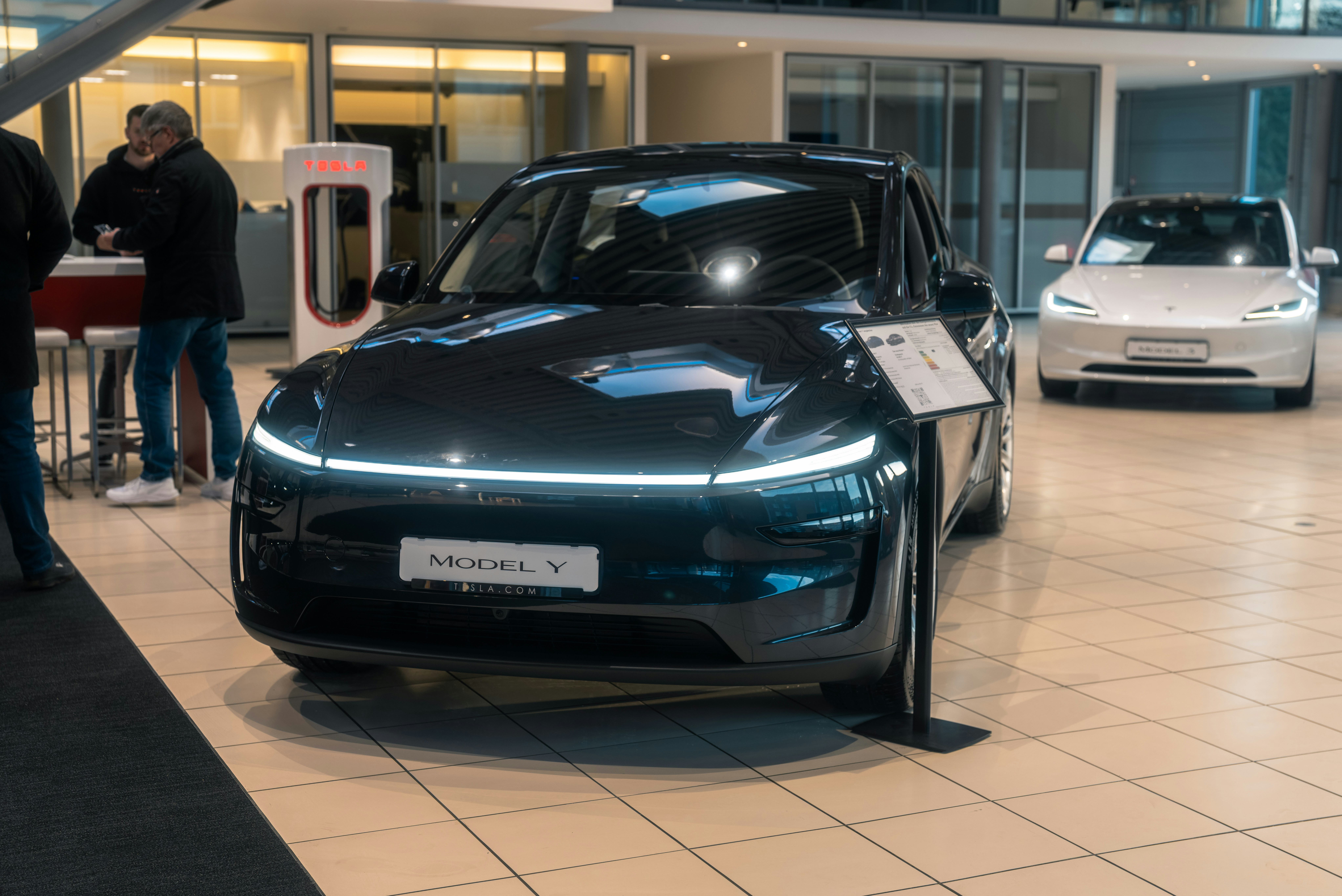 Driver holding keys and smiling next to a used electric car