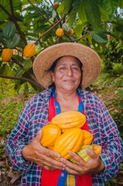 A woman in a straw hat holding a bunch of melons