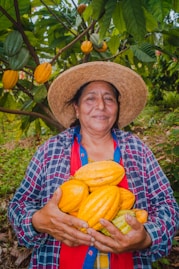 A woman in a straw hat holding a bunch of melons