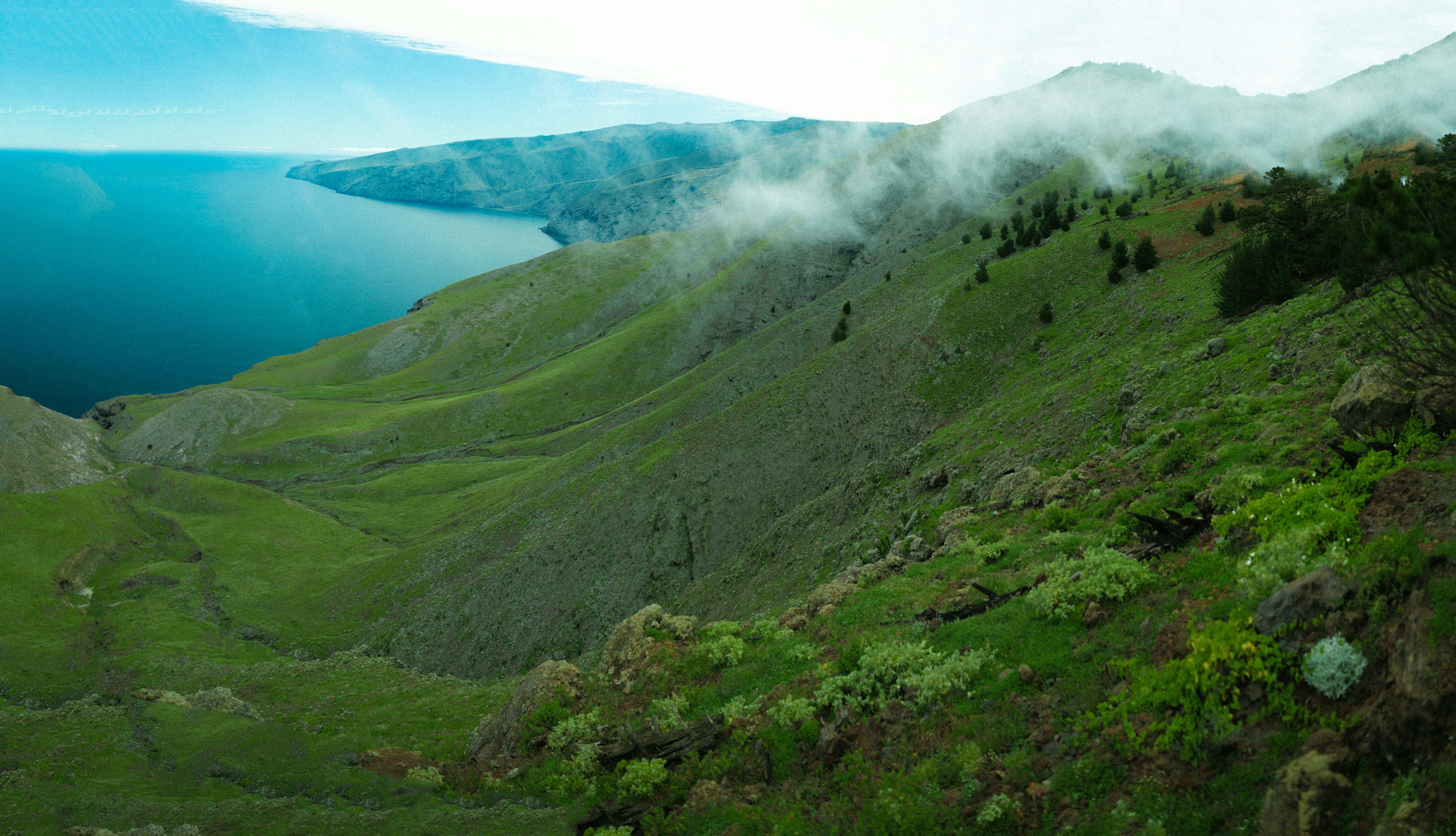 A scenic view of a valley with a body of water in the distance