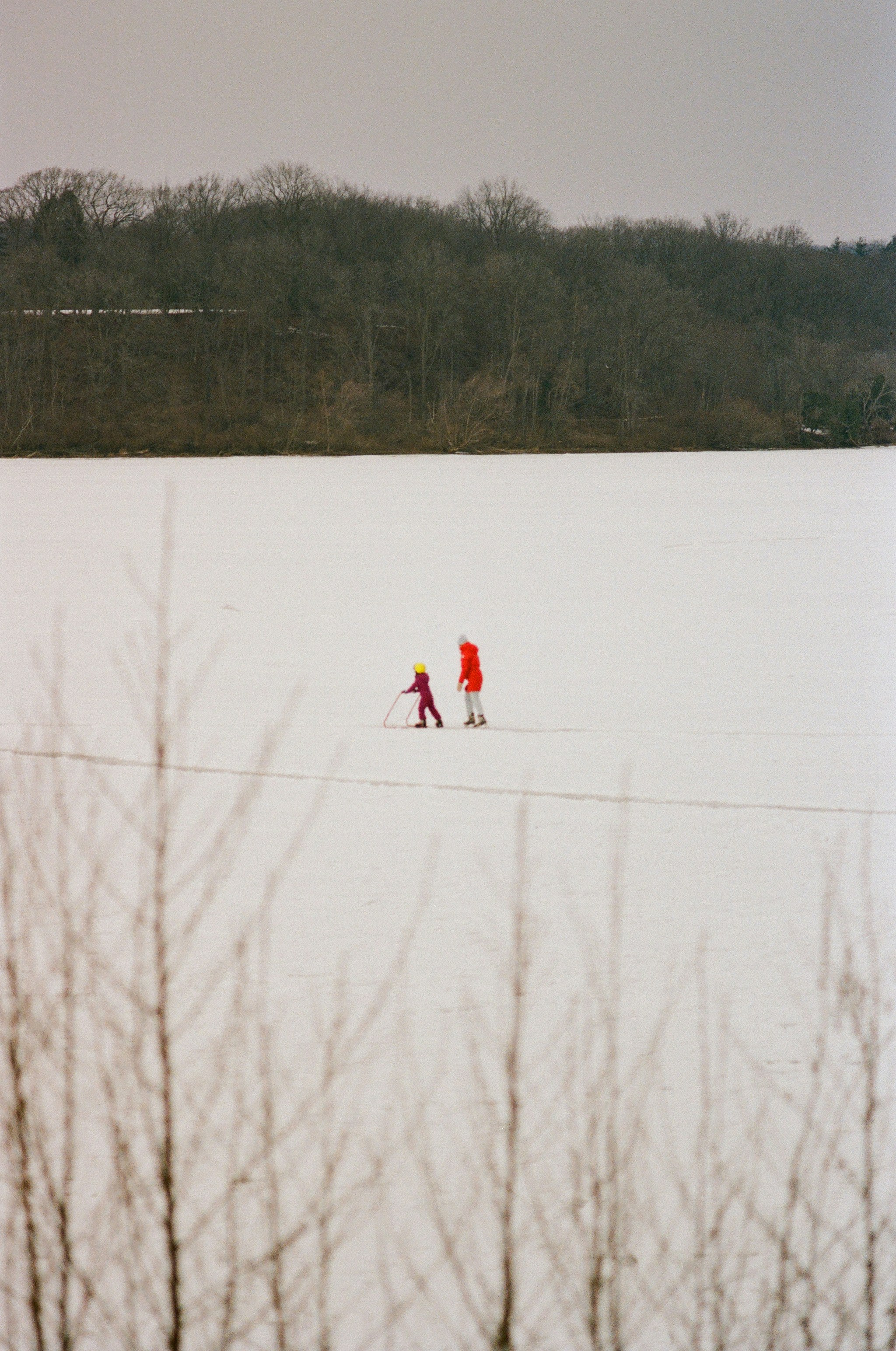 A couple of people walking across a snow covered field