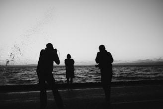 A group of people standing on top of a beach next to the ocean
