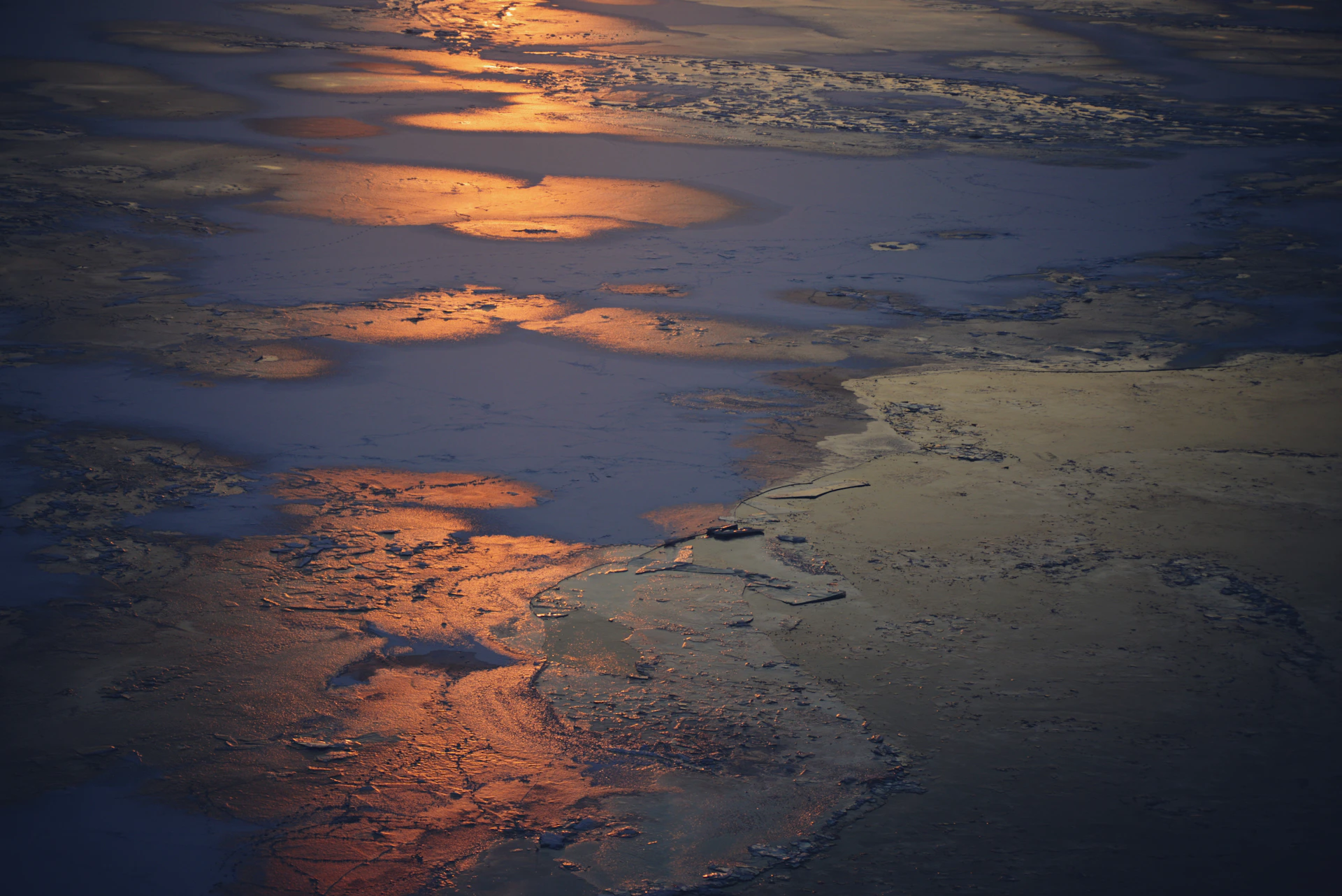 The sun is setting over the ocean as seen from an airplane