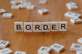 Scrabbled letters spelling the word border on a wooden table