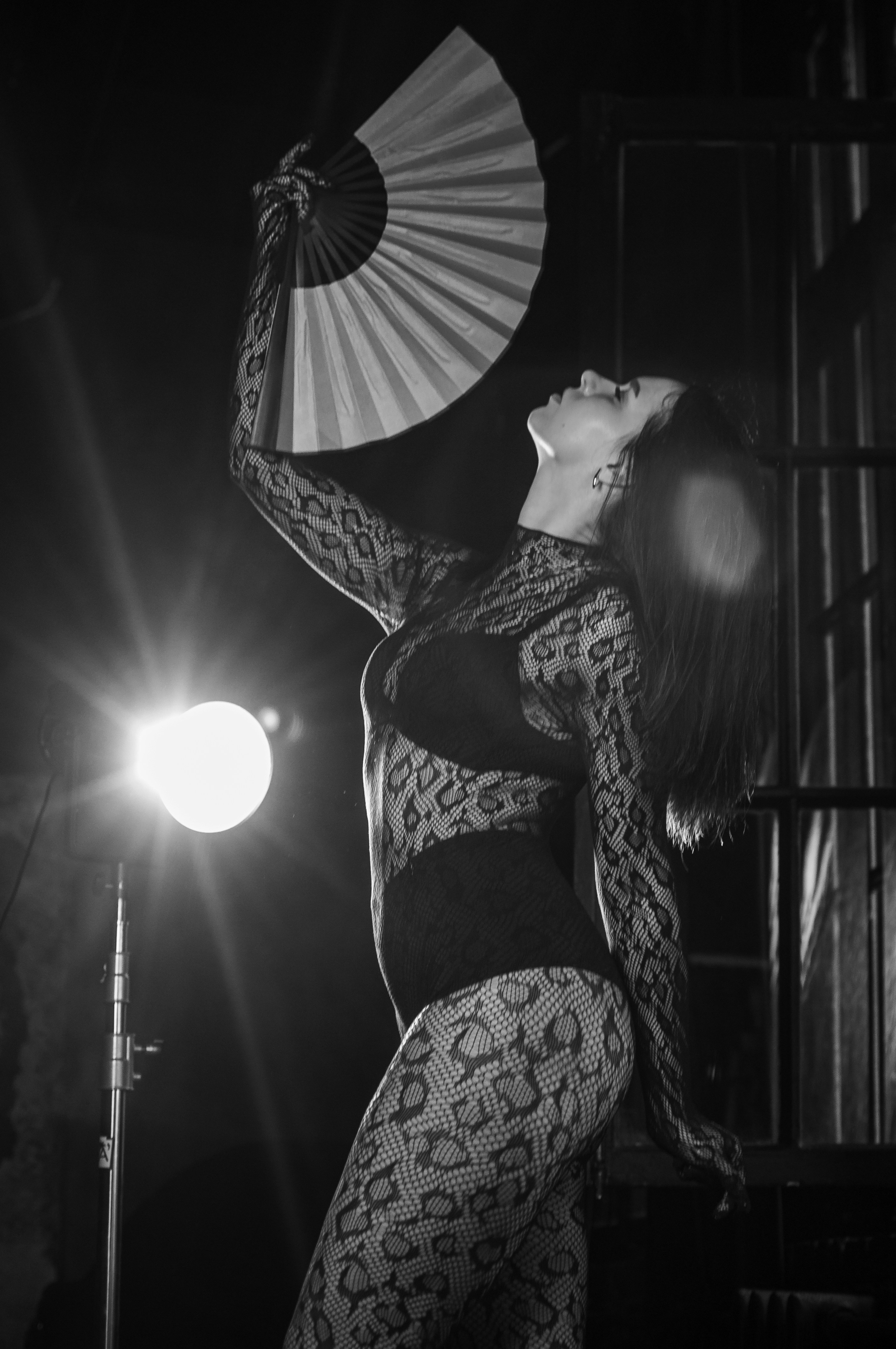 A woman in a bodysuit holding a fan