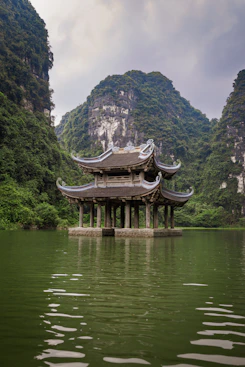 A pagoda in the middle of a lake surrounded by mountains