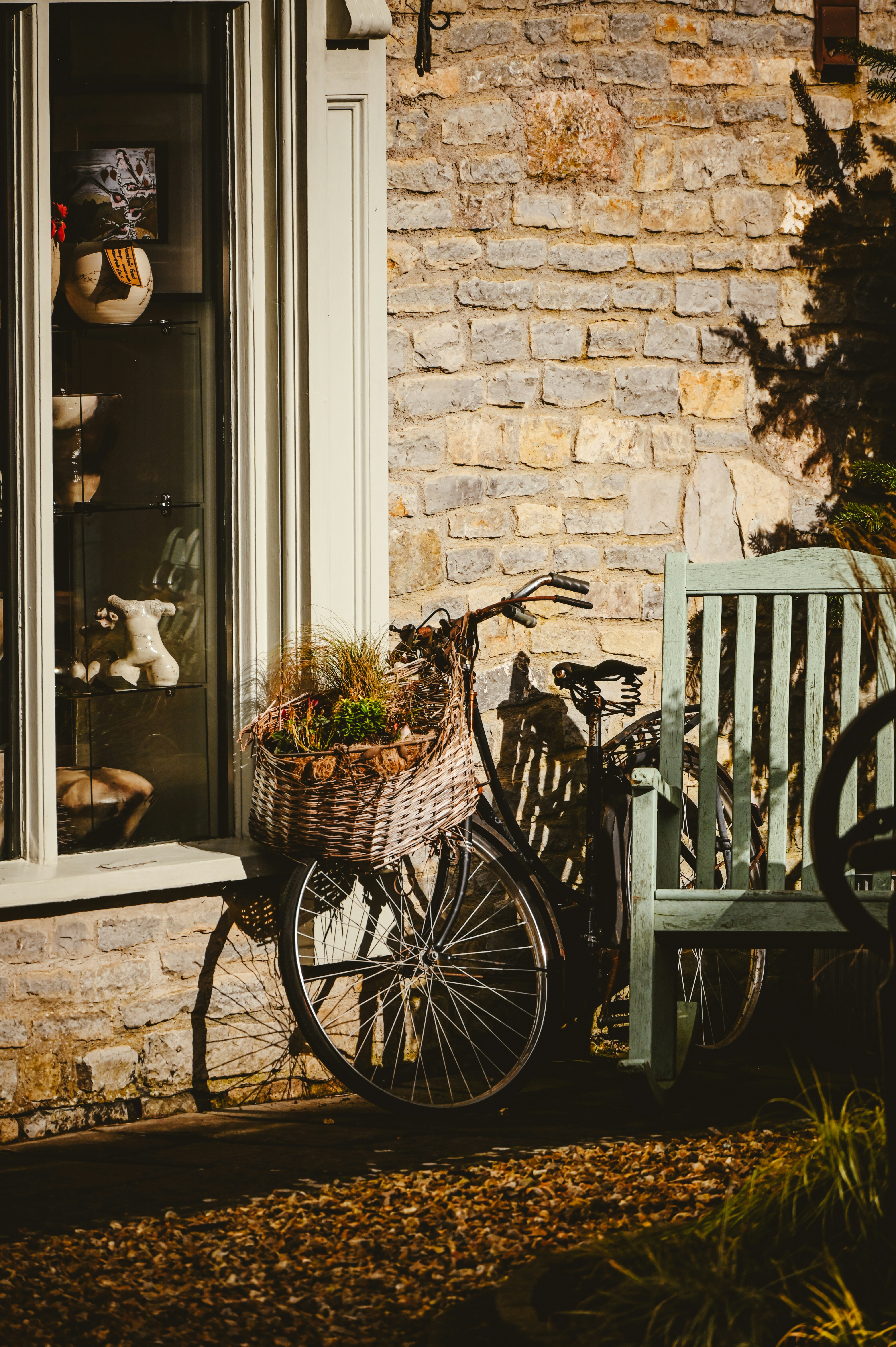 A bicycle parked next to a bench in front of a window