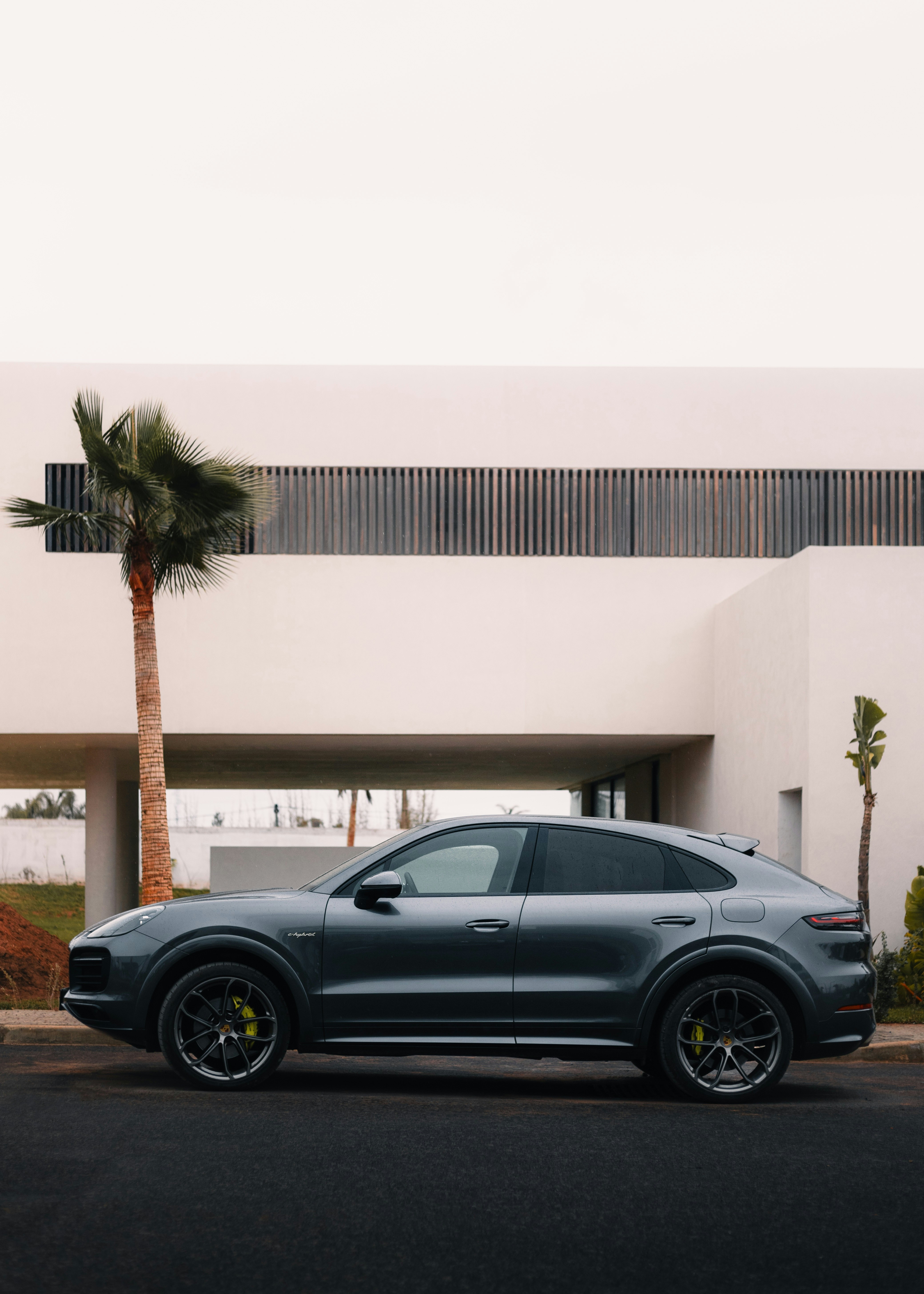 A grey porsche cayen is parked in front of a building