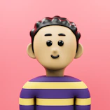 A small toy is standing in front of a pink background