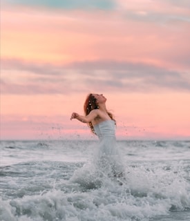 A woman in a white dress standing in the ocean
