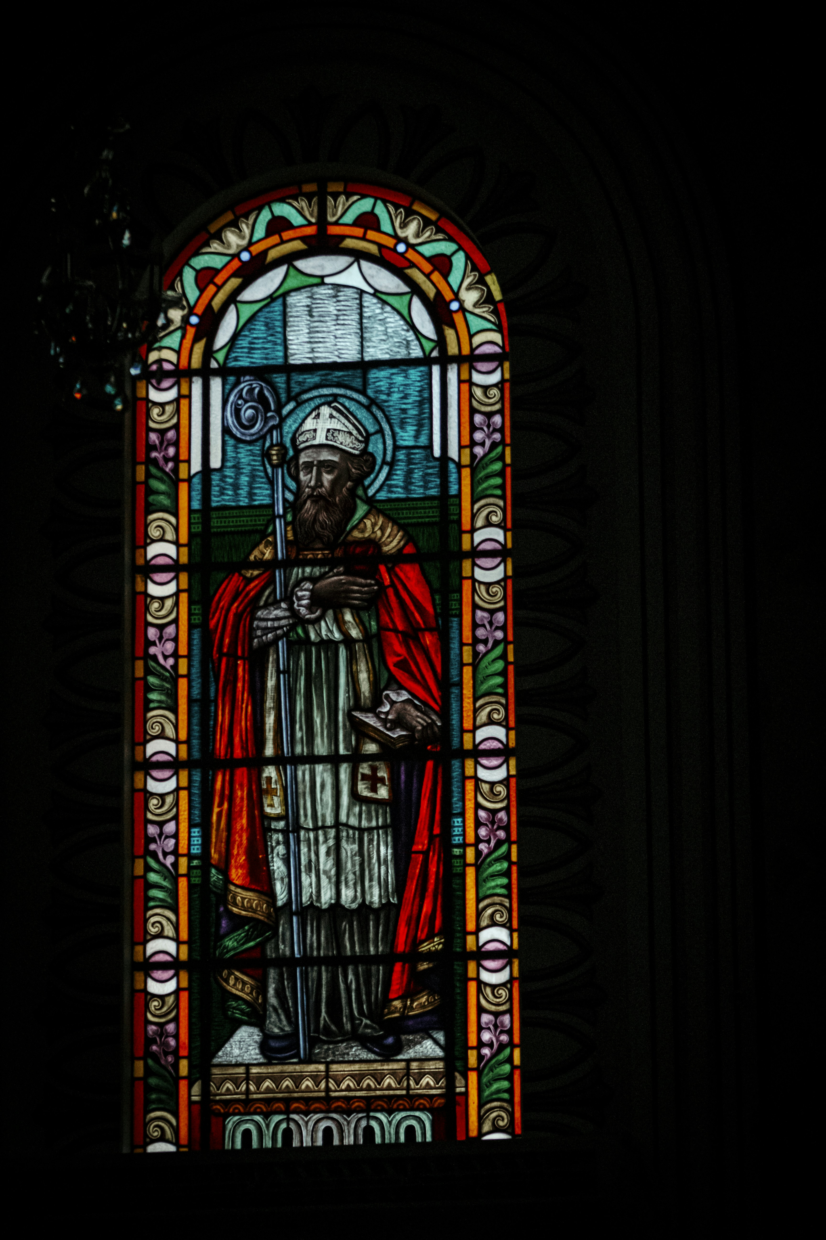 A stained glass window with a man holding a cross