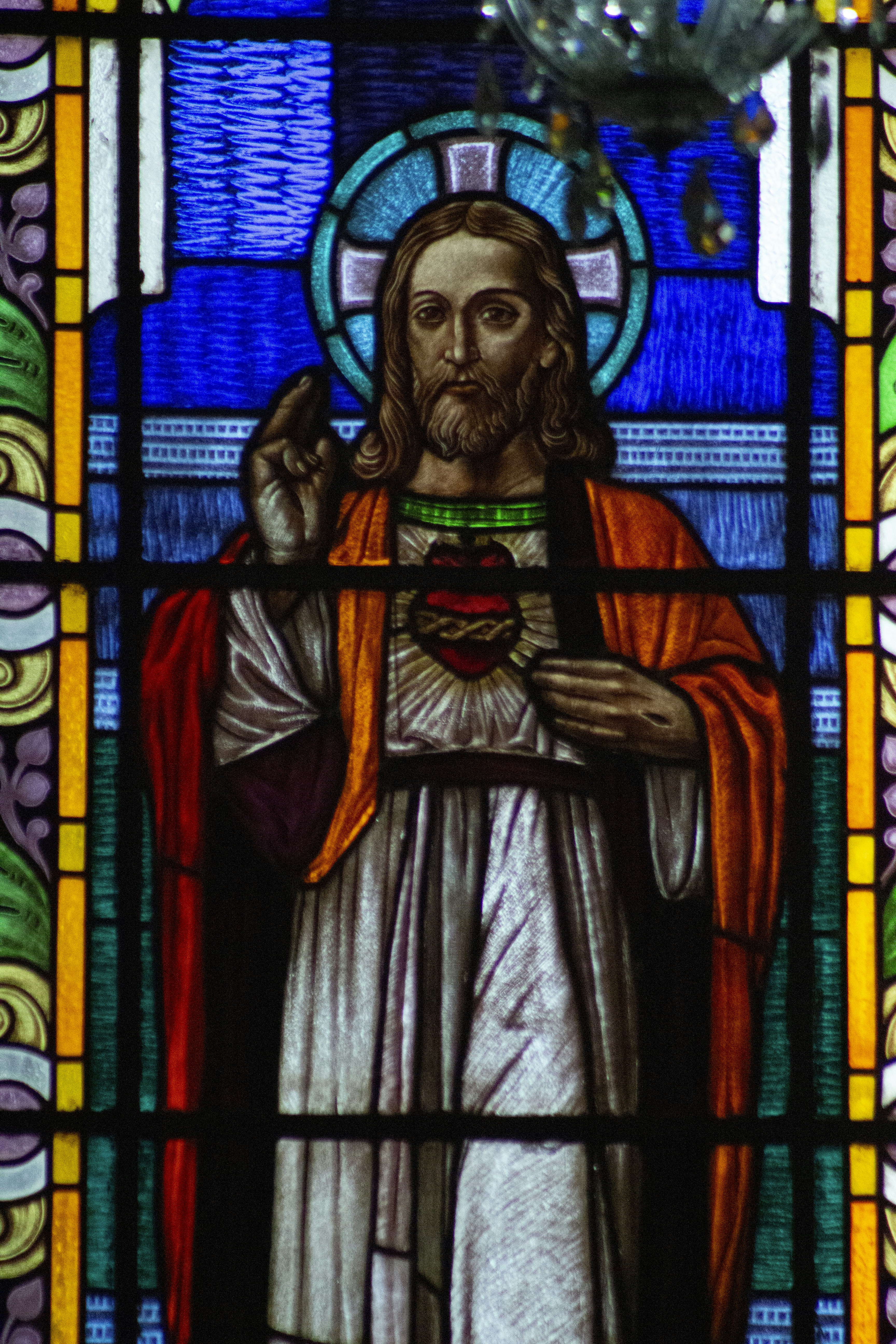 A stained glass window with jesus holding a cross