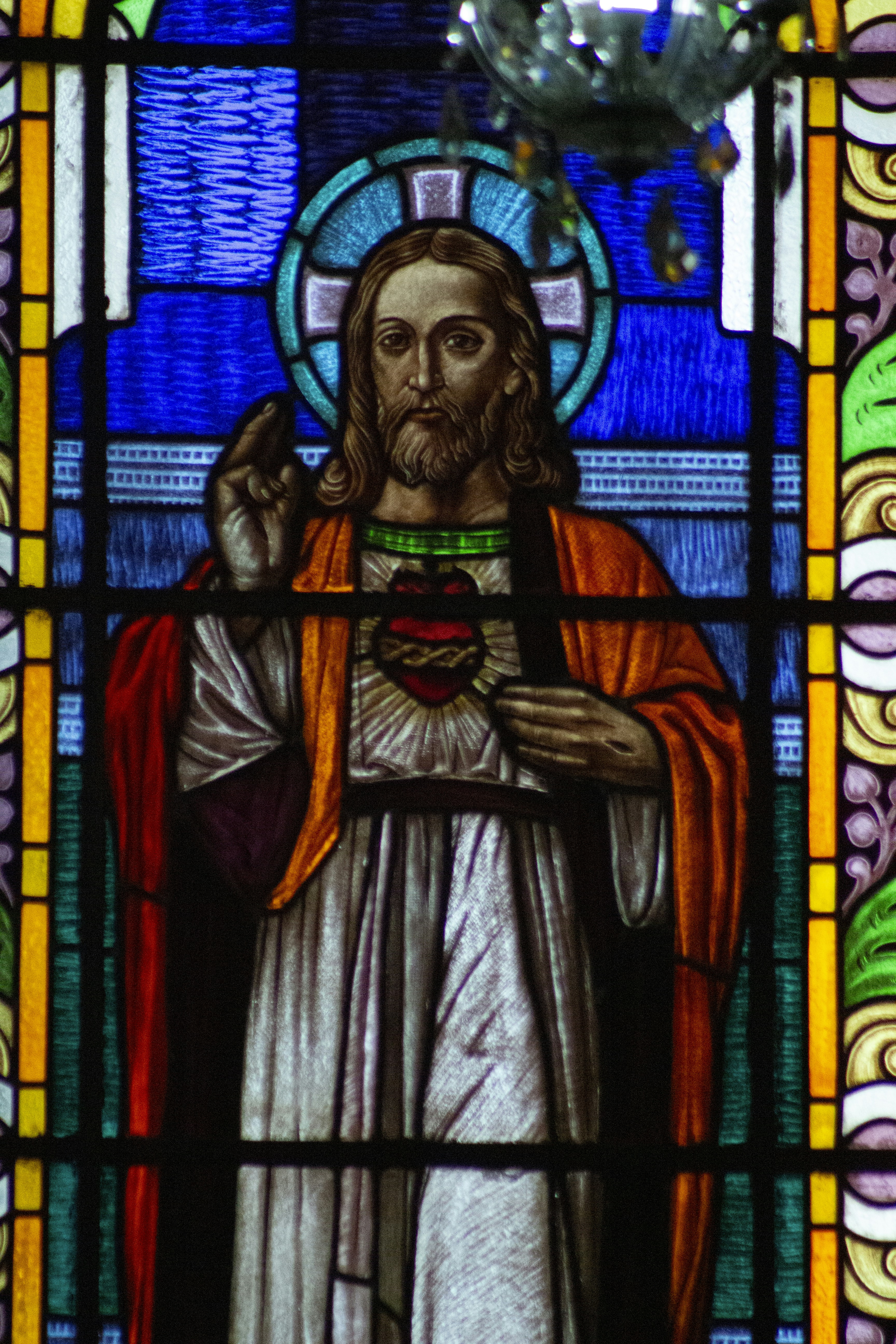 A stained glass window with a man holding a cross