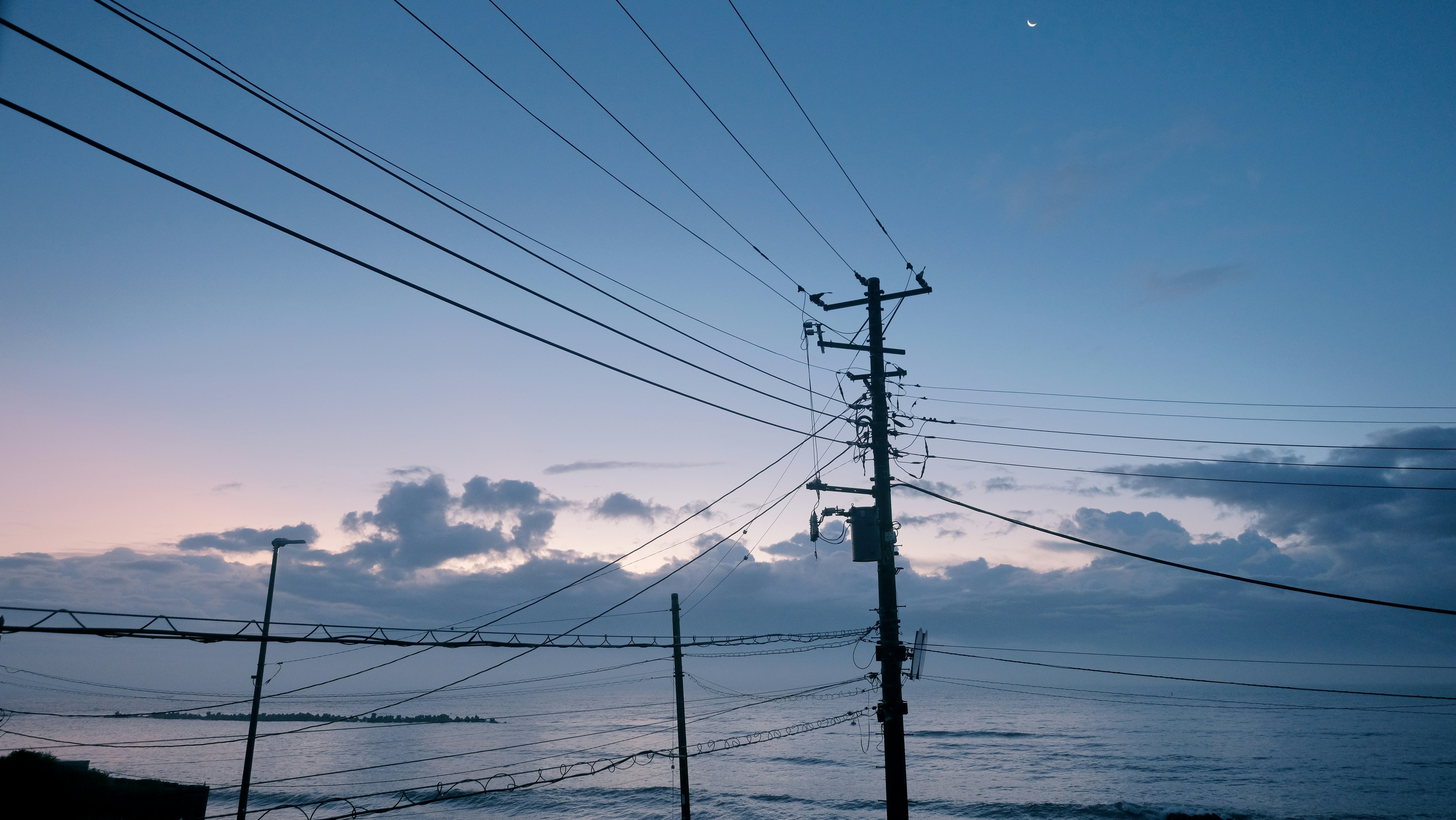 Power lines and telephone poles against a blue sky