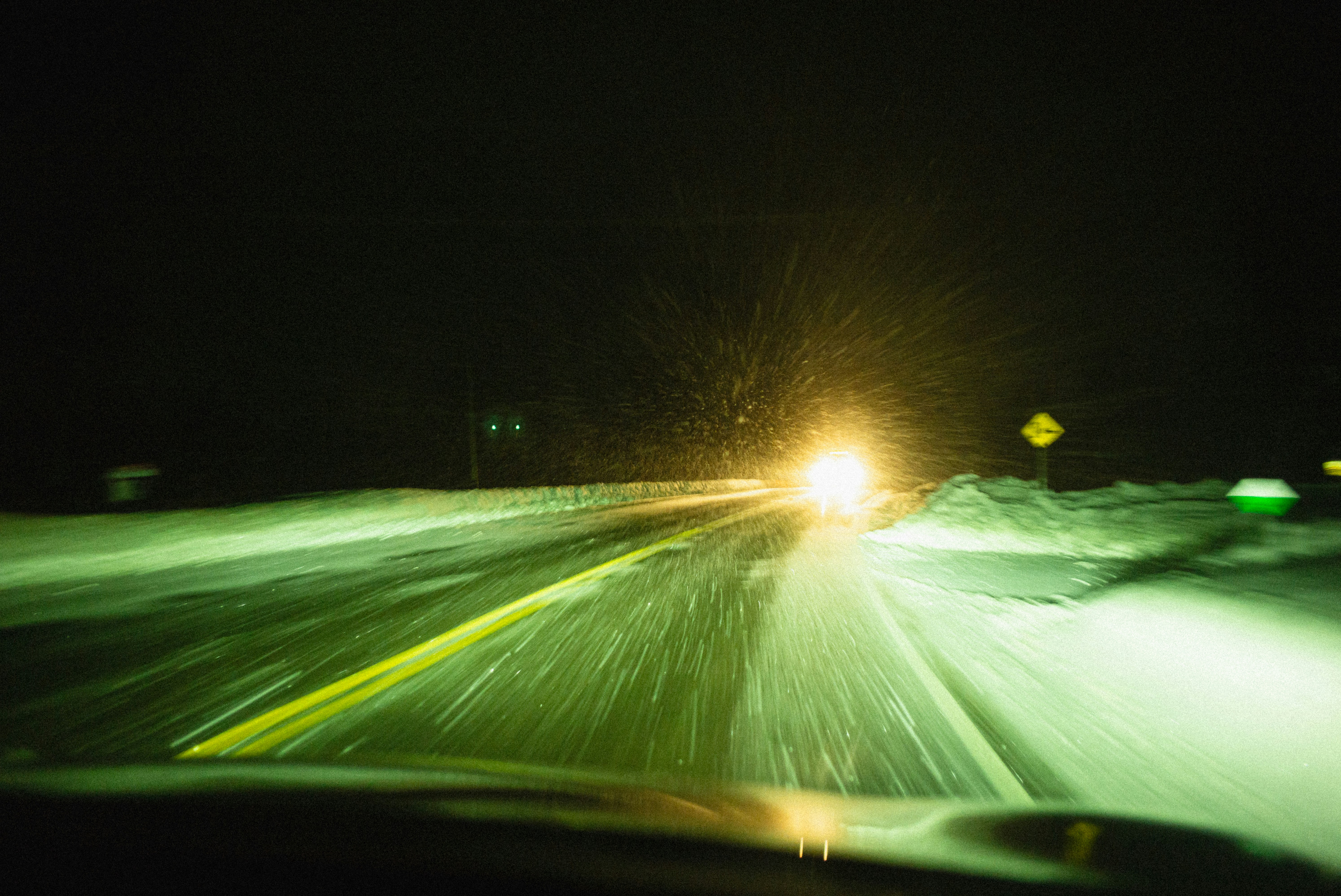 A car driving down a snowy road at night