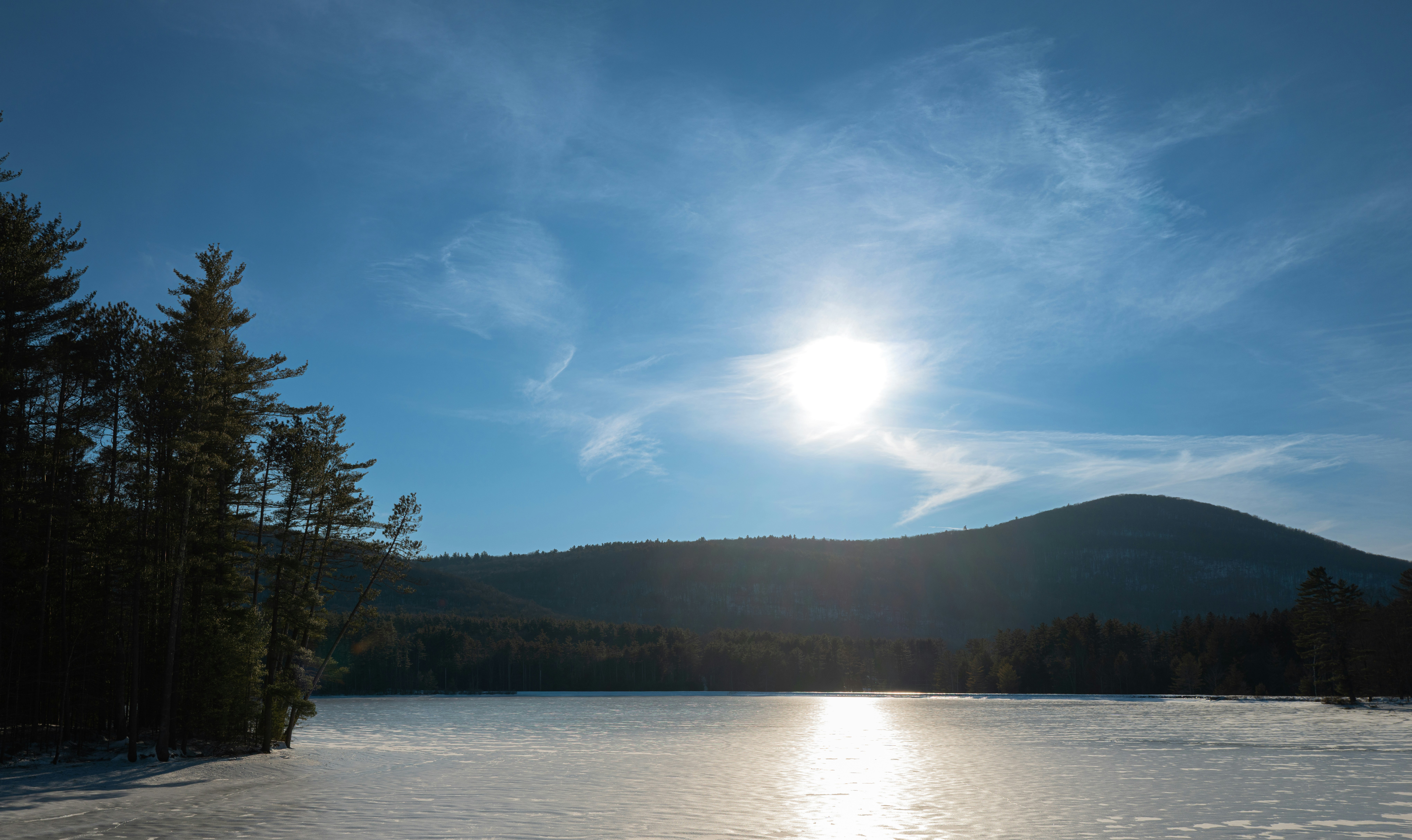 The sun shines brightly over a frozen lake