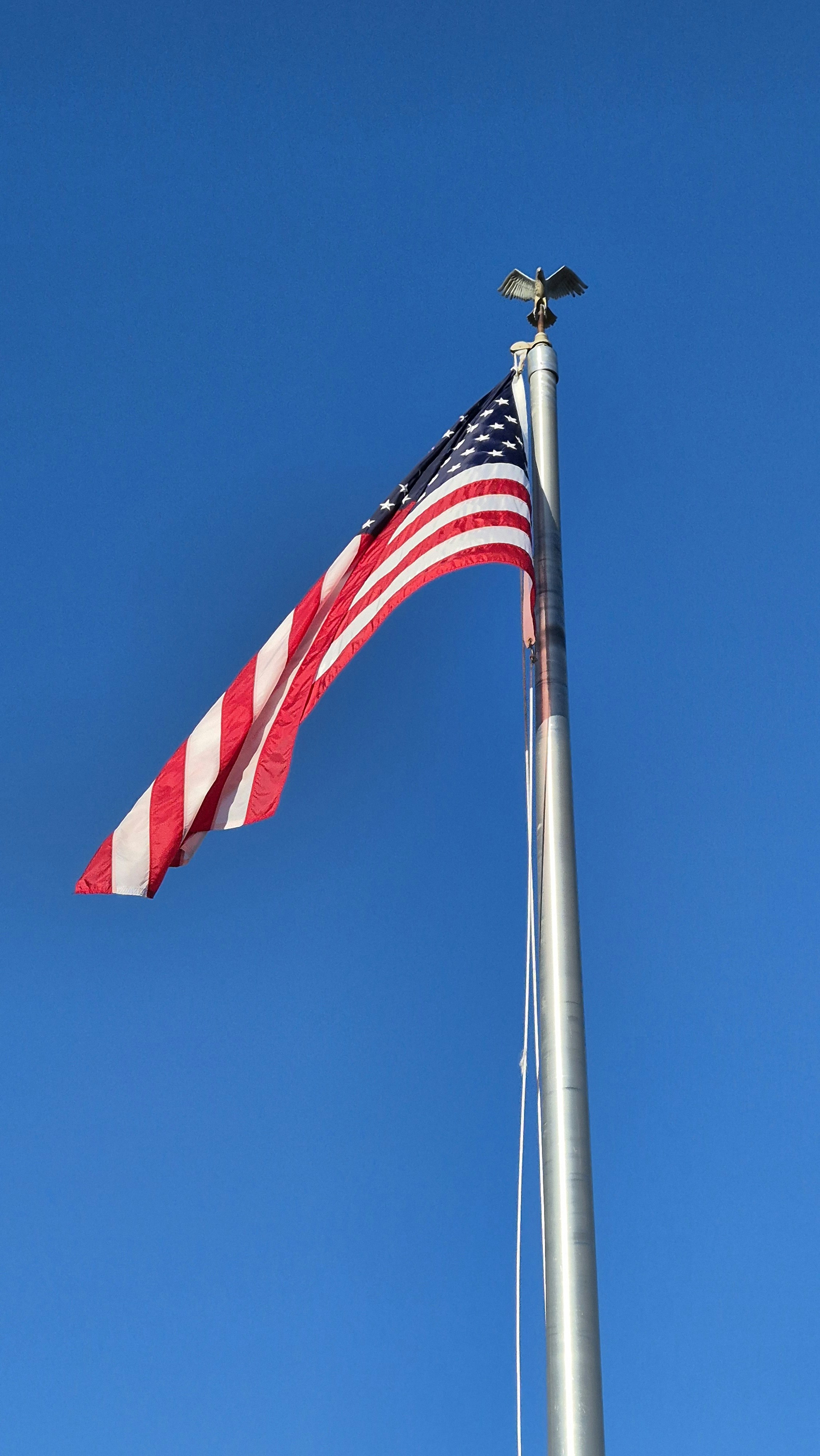 An american flag flying high in the blue sky